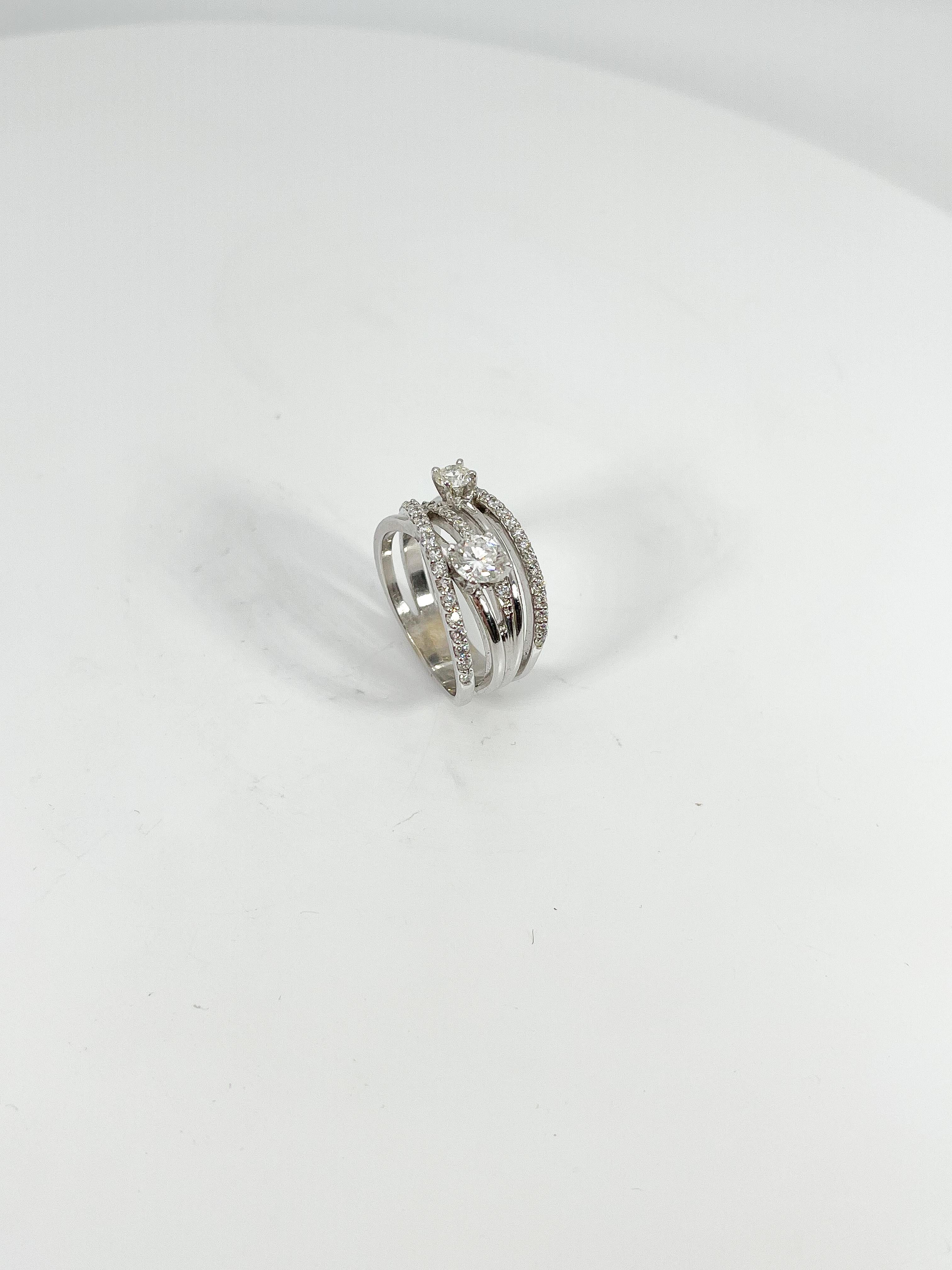 14k white gold 1.5 CTW diamond fashion crossover ring. Two larger diamonds are .50 CTS and .15 CTS. The melee diamonds are .85 CTW. The ring is 11.1 mm in width, measures to be a size 6 3/4, and has a weight of 7.6 grams 