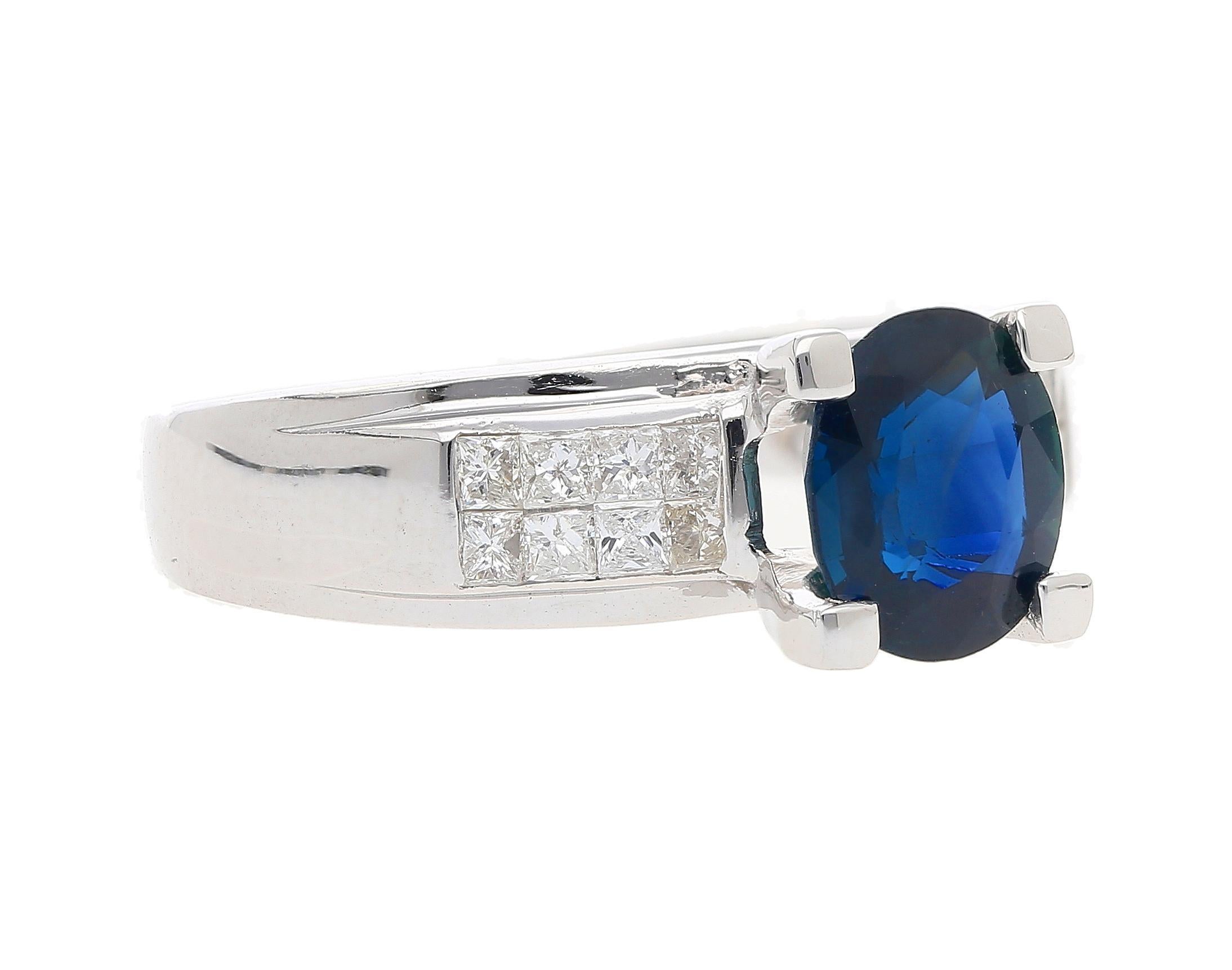 This 14K white gold sapphire ring features 16 princess-cut diamonds of 1/2 CTTW set in invisible tension cluster setting. The diamonds on either side of the shank compliment the 1.56 CT oval-cut blue sapphire at the center. The ring in its totality