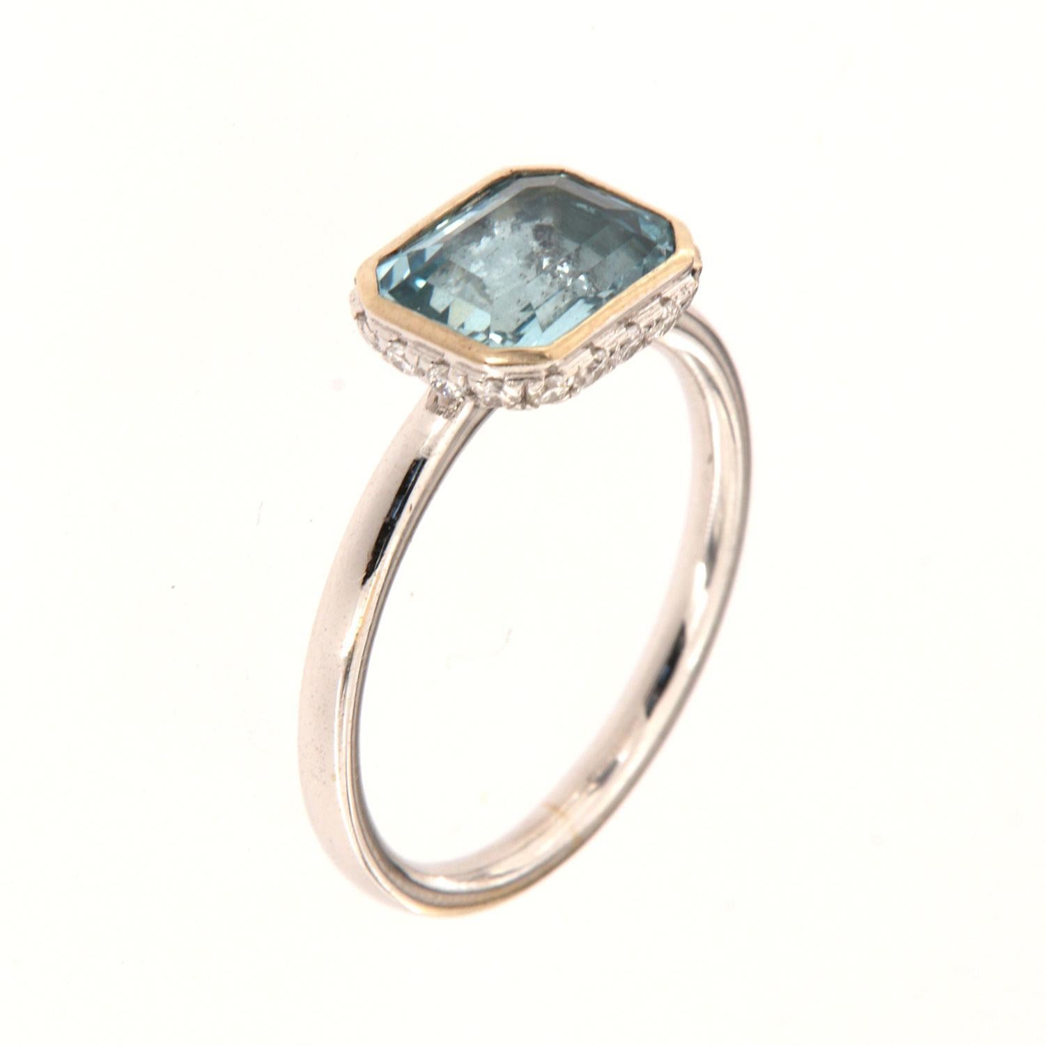 This 14k White gold delicate ring features a 1.70 Carat Blue Aquamarine emerald cut bezel set East-West style. Sixteen (16)Brilliant round diamonds are micro-prong set in a hidden halo on the crown to create the sparkle look every woman is looking