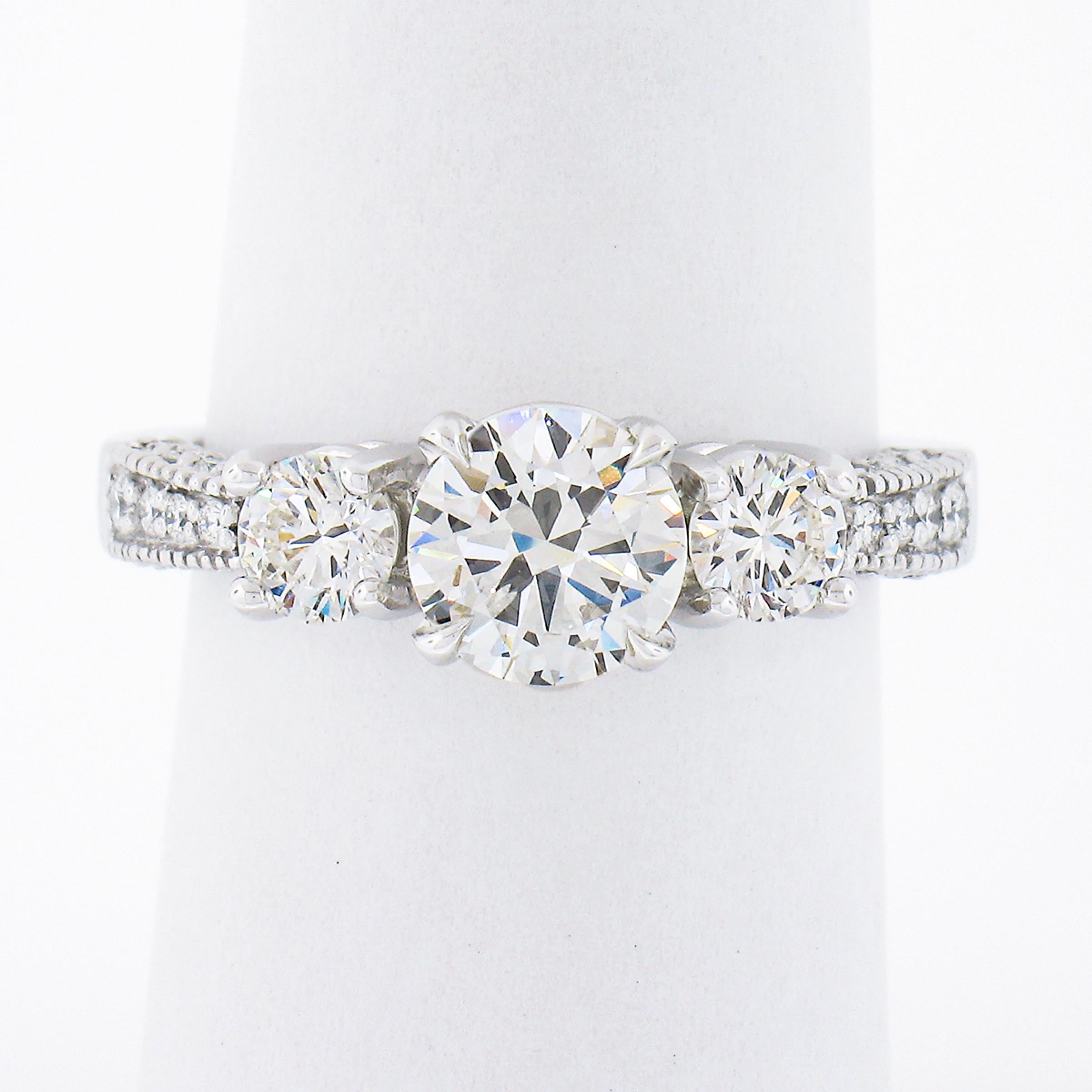 This elegant and chic three stone diamond engagement ring is crafted in solid 14k white gold and features a gorgeous round brilliant cut diamond solitaire, claw-prong set at the center of the design. This center stone is GIA certified, weighs
