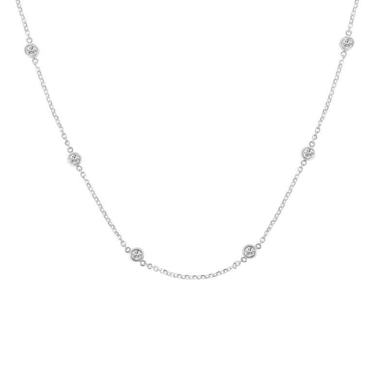 A great complement to both dressy and casual wear, this 14kt white gold, diamond station necklace is extremely trendy, classy, and fashionable. Twelve brilliant cut round diamonds, weighing 1 carat in total, sparkle in 12 bezel settings spread