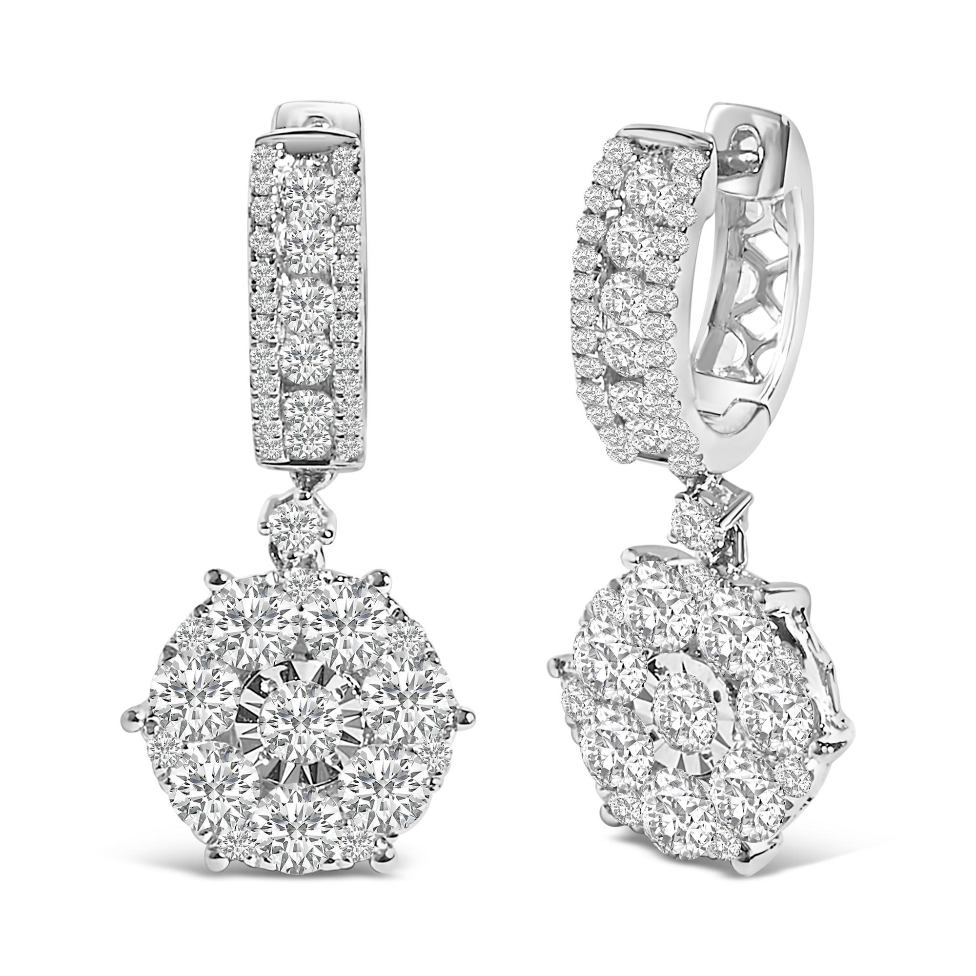 Tauchen Sie ein in die opulente Umarmung dieser prächtigen Ohrringe, die meisterhaft aus poliertem 14-karätigem Weißgold mit Rhodium-Finish gefertigt sind und einen unvergleichlichen Glanz versprühen. Natürliche Diamanten im Rundschliff mit einem