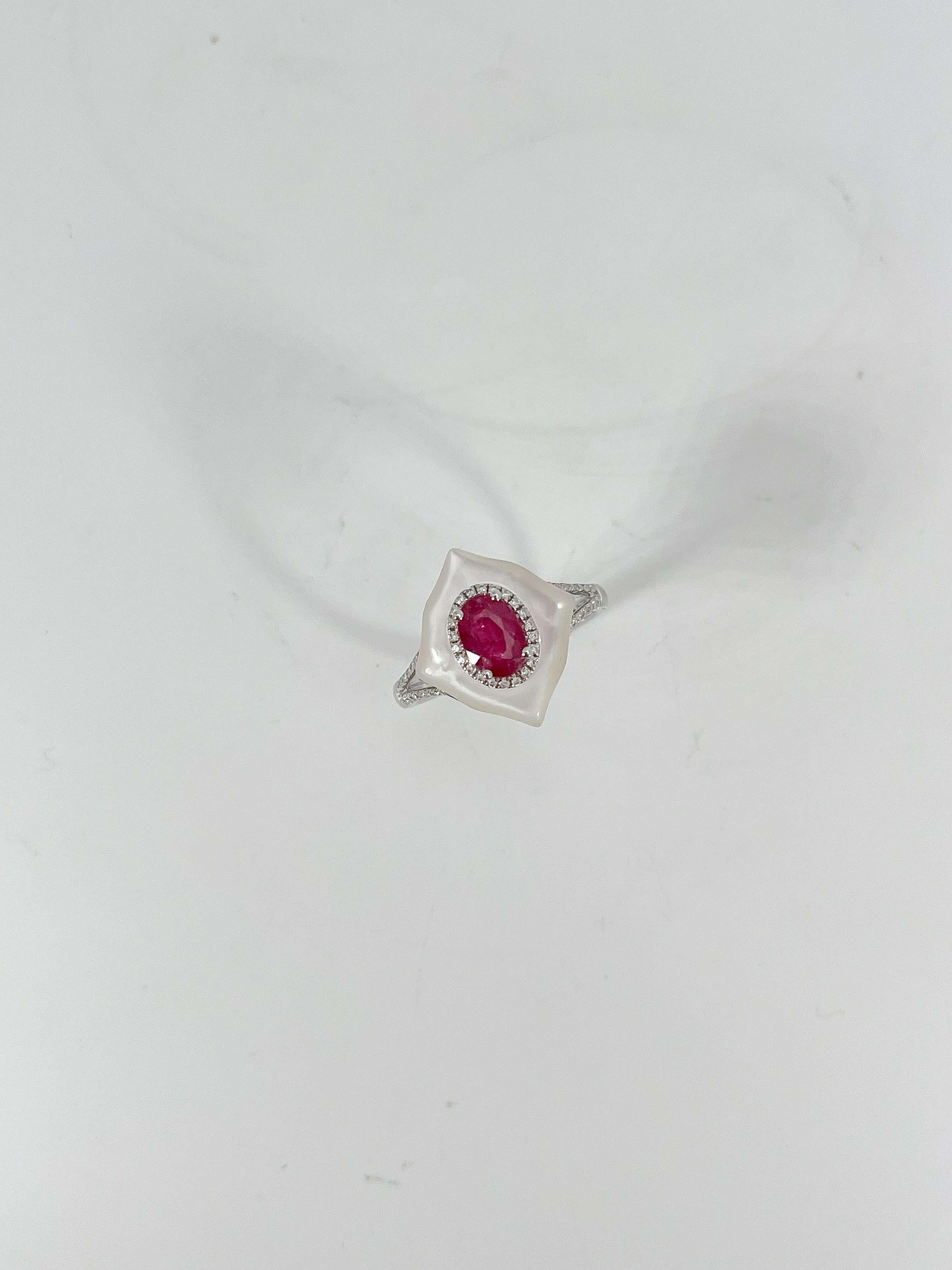 14k white gold 1.10 CTW oval ruby center stone surrounded by 2.14 CTW mother of pearl, and .14 CTW round diamonds on the sides and a halo around the ruby. This ring is a size 7, the center stone measures 6.8mm x 4.8mm, the mother of pearl design