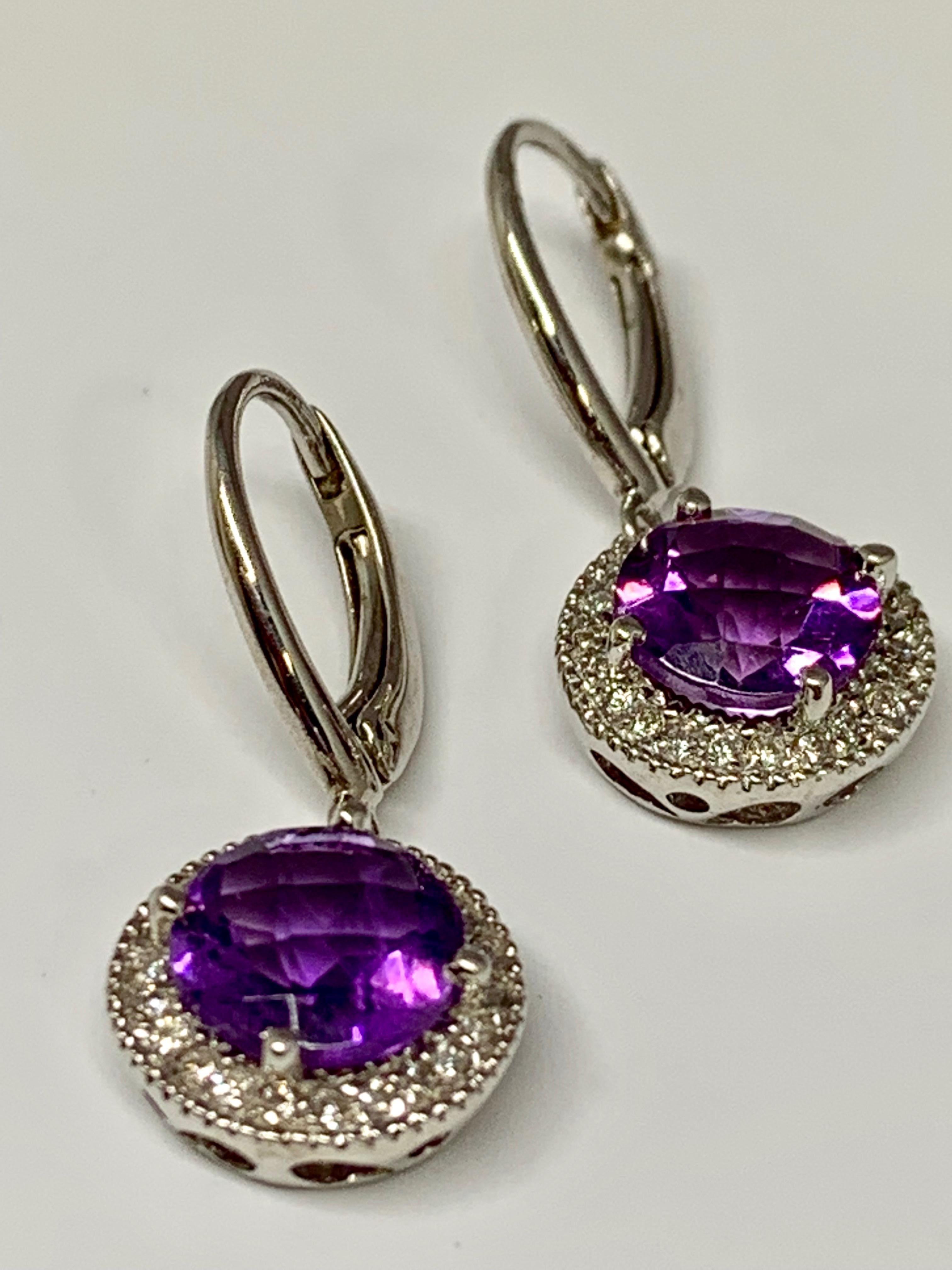These 14K white gold lever-back earrings hold a 1.04 carat round checkerboard cut amethyst each, for a total amethyst weight of 2.08 carats. Surrounding each amethyst is a micro pave diamond halo holding 0.08 carats of round white diamonds each. The