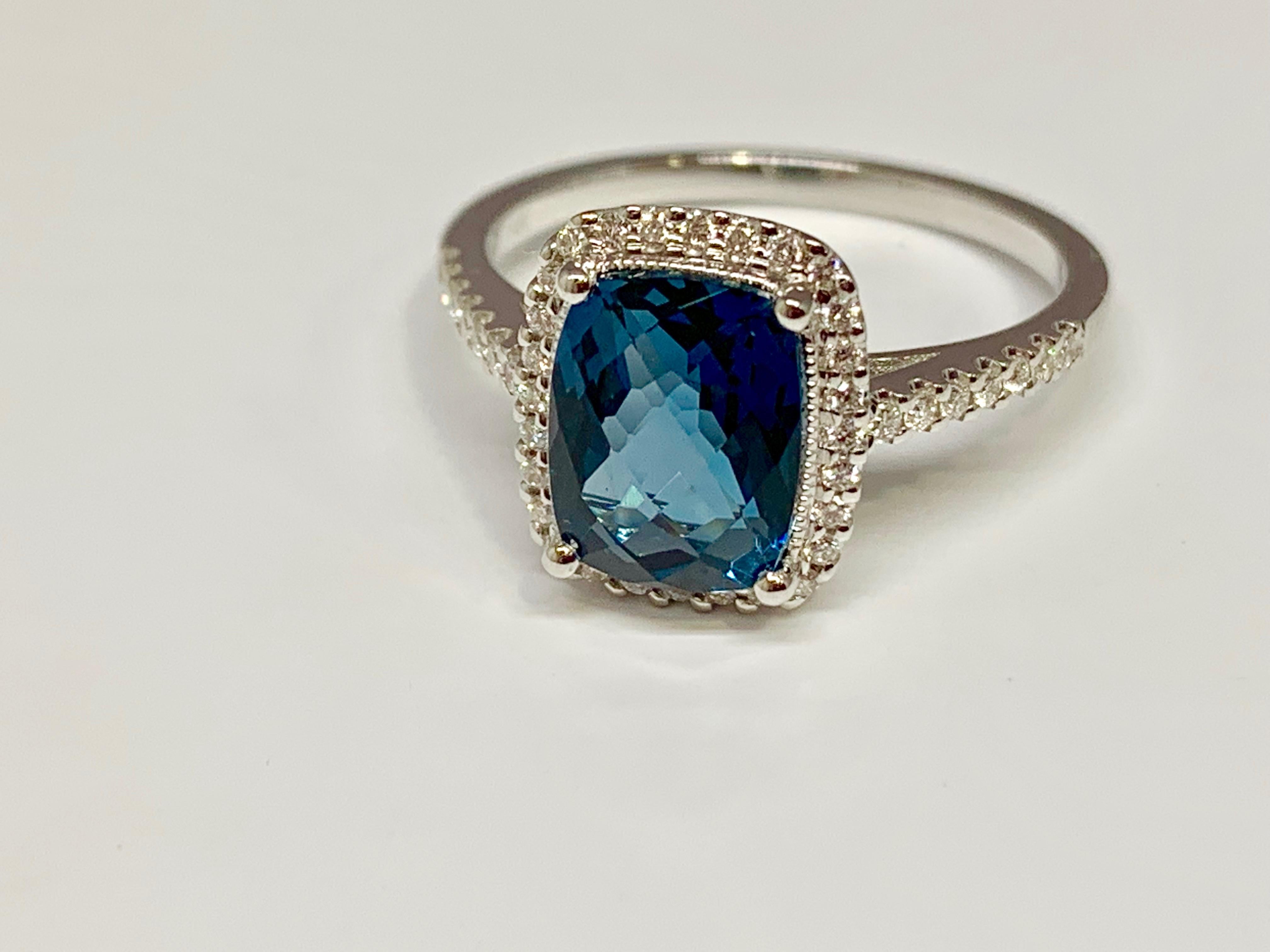 This Allison-Kaufman Company cocktail ring holds a stunning deep blue topaz cushion cut center stone with checkerboard faceting. The classic 14K white gold micro pave diamond mounting is currently a size 6.5 but can be resized upon request. This