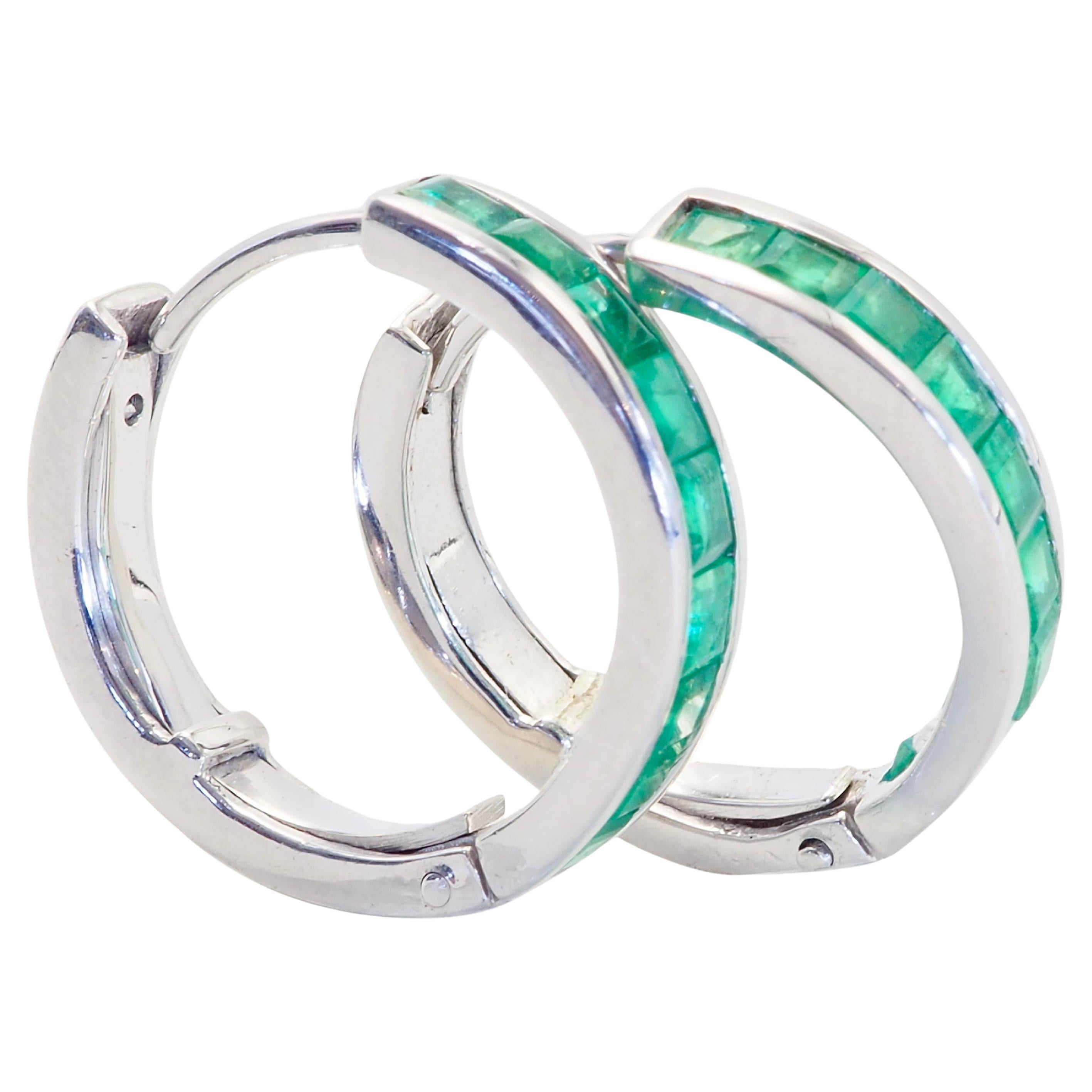 Beautiful and unique earrings made in the early 2000s and has never been worn. The earrings are hoop style and is intricately designed. There are 18 squared vivid green emeralds in total and therefore 9 for each ear. They are neatly set into