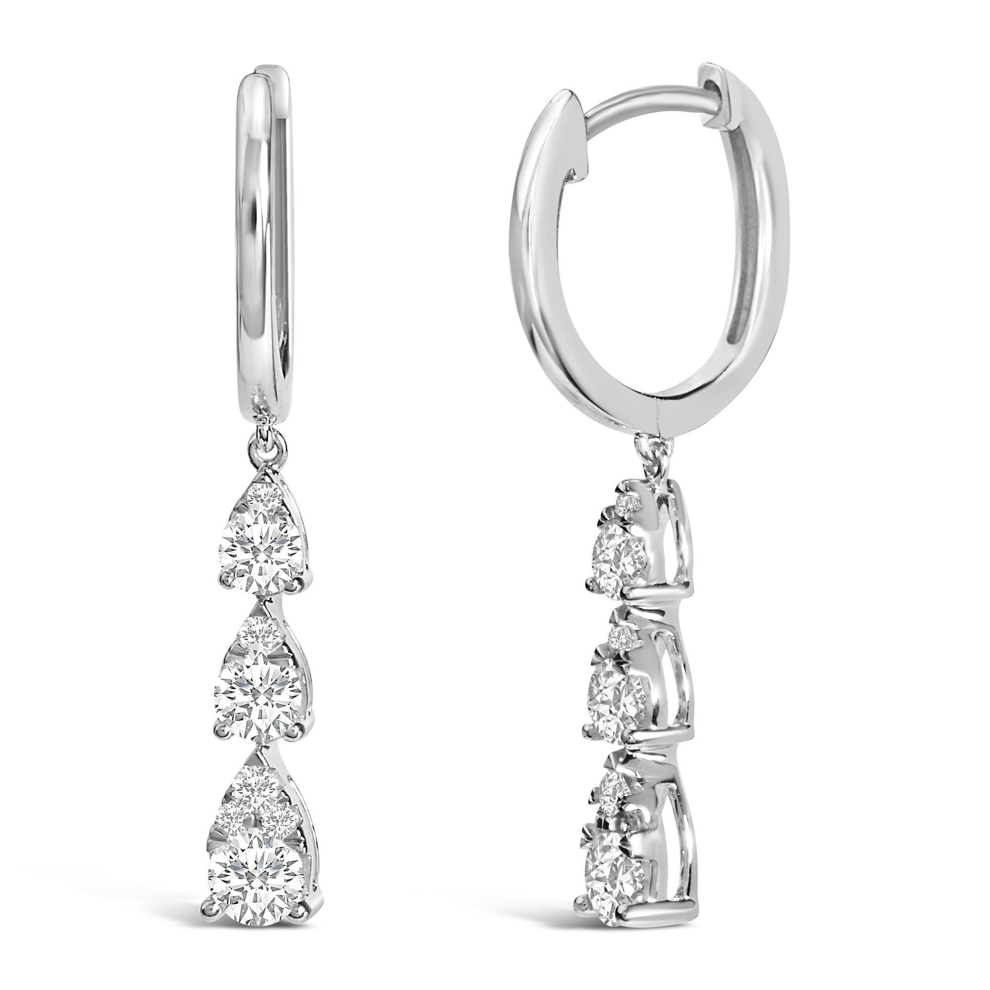 Plongez dans le monde de la sophistication exquise avec ces boucles d'oreilles en or blanc 14 carats, où l'élégance cascade sans effort. Plaqué en rhodium pour une brillance inégalée, leur design unique met en valeur un trio de grappes de diamants