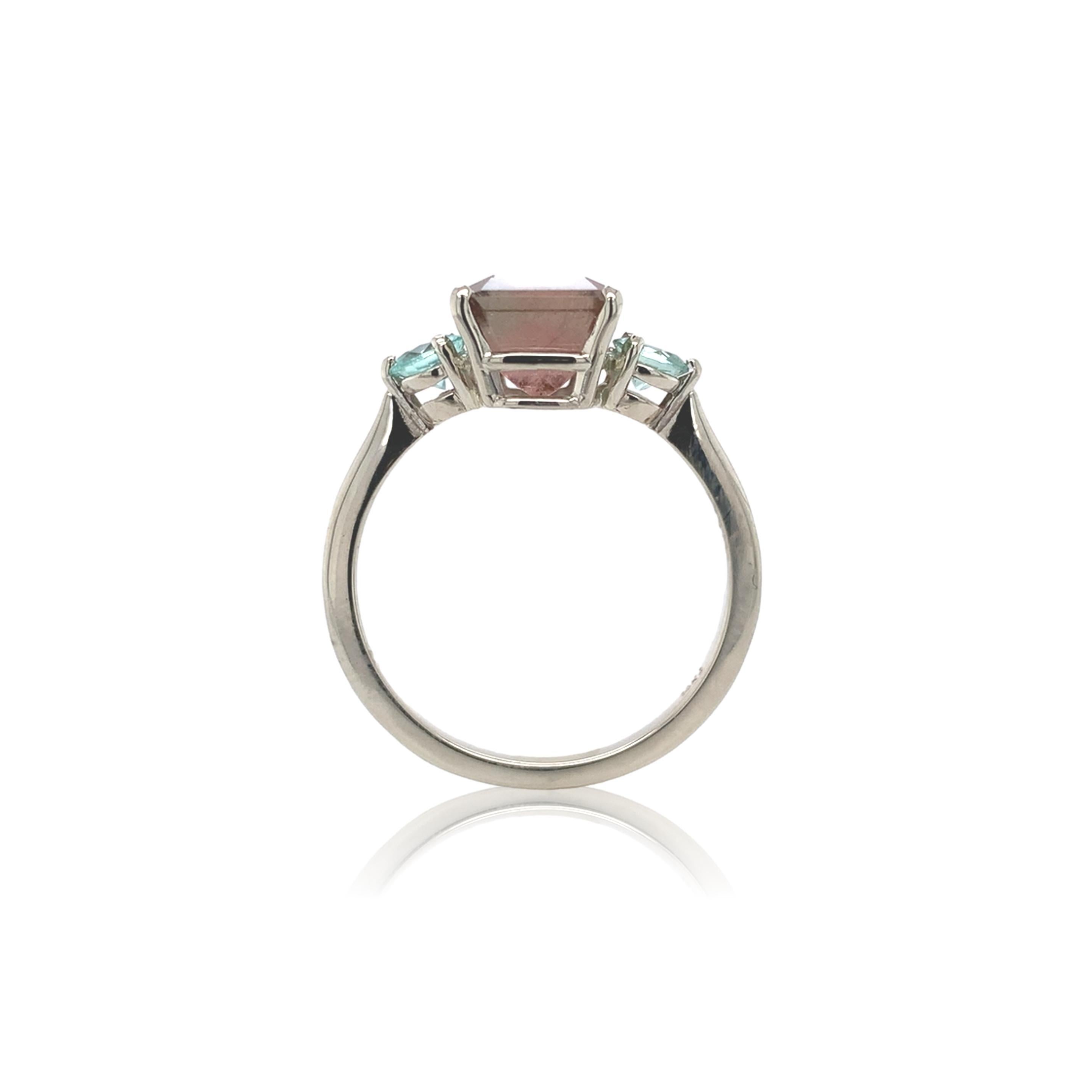 A 14K white gold ring featuring a bi-color watermelon tourmaline weighing 3.80 carats. The tourmaline has soft pale color from pale pink to light sea blue-green. The tourmaline is an emerald cut and measures about 8.9mm x 7.7mm. There are 2 round