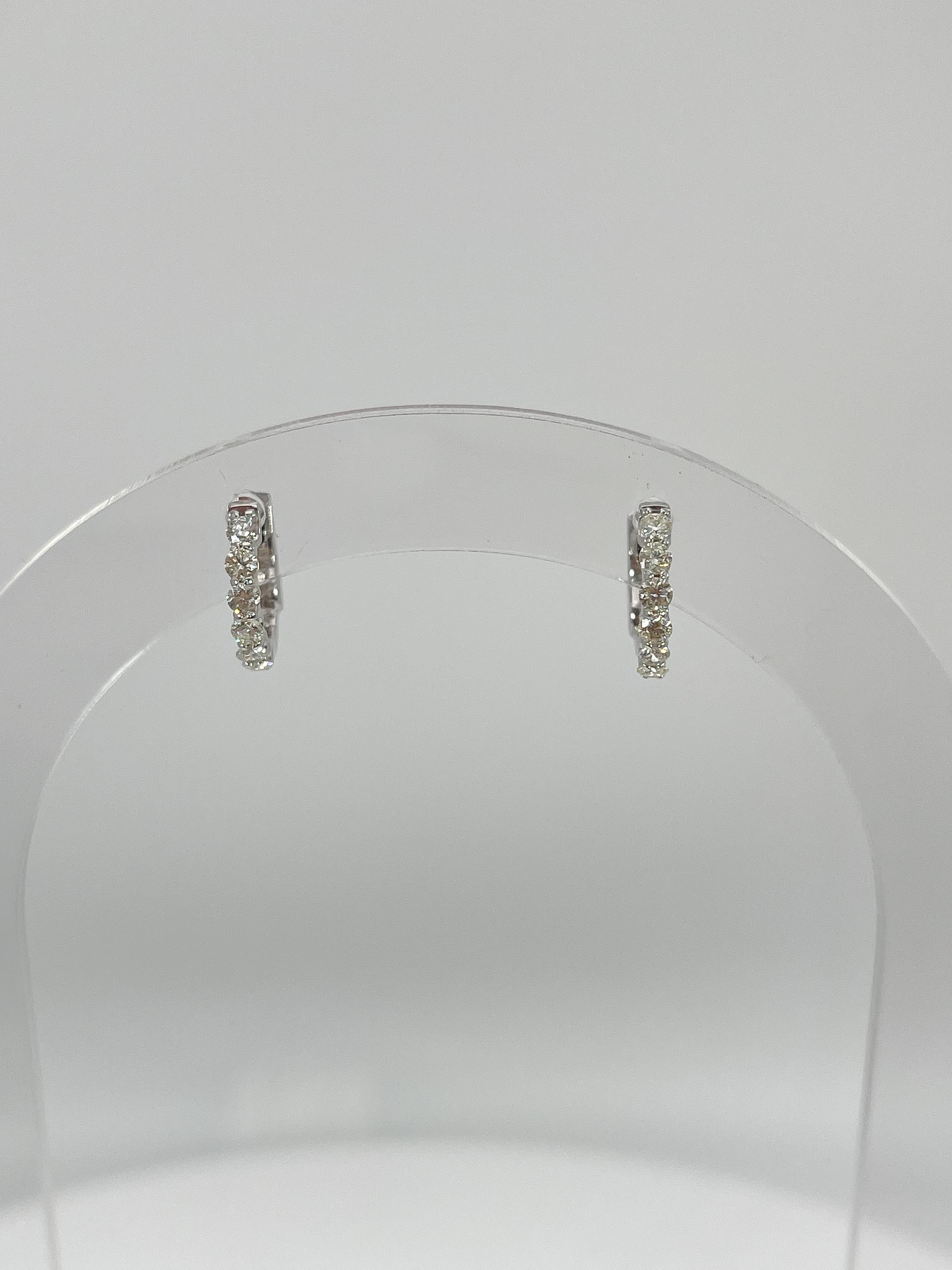 14k white gold .47 CTW diamond huggie hoop earrings. All the diamonds in these earrings are round, they have measurements of 12mm x 2 mm, they have a safety clasp to open and close earrings, and they have a total weight of 2.3 grams.
