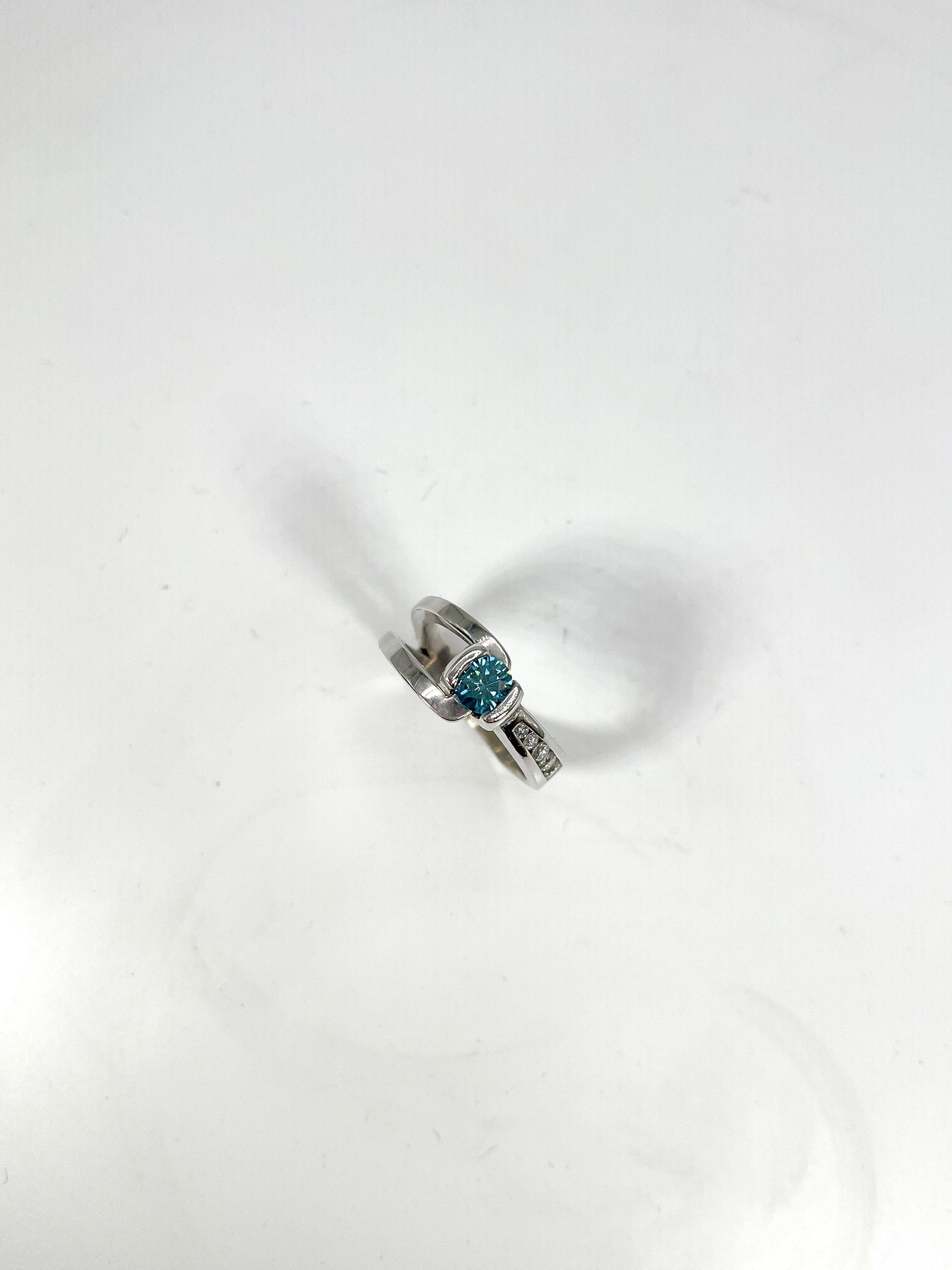 14k white gold .50 CT irradiated blue diamond and .60 CTW white diamond ring. All stones in this ring are round, the width is 8.7 mm, the size is a 6, and it has a total weight of 8.3 grams.