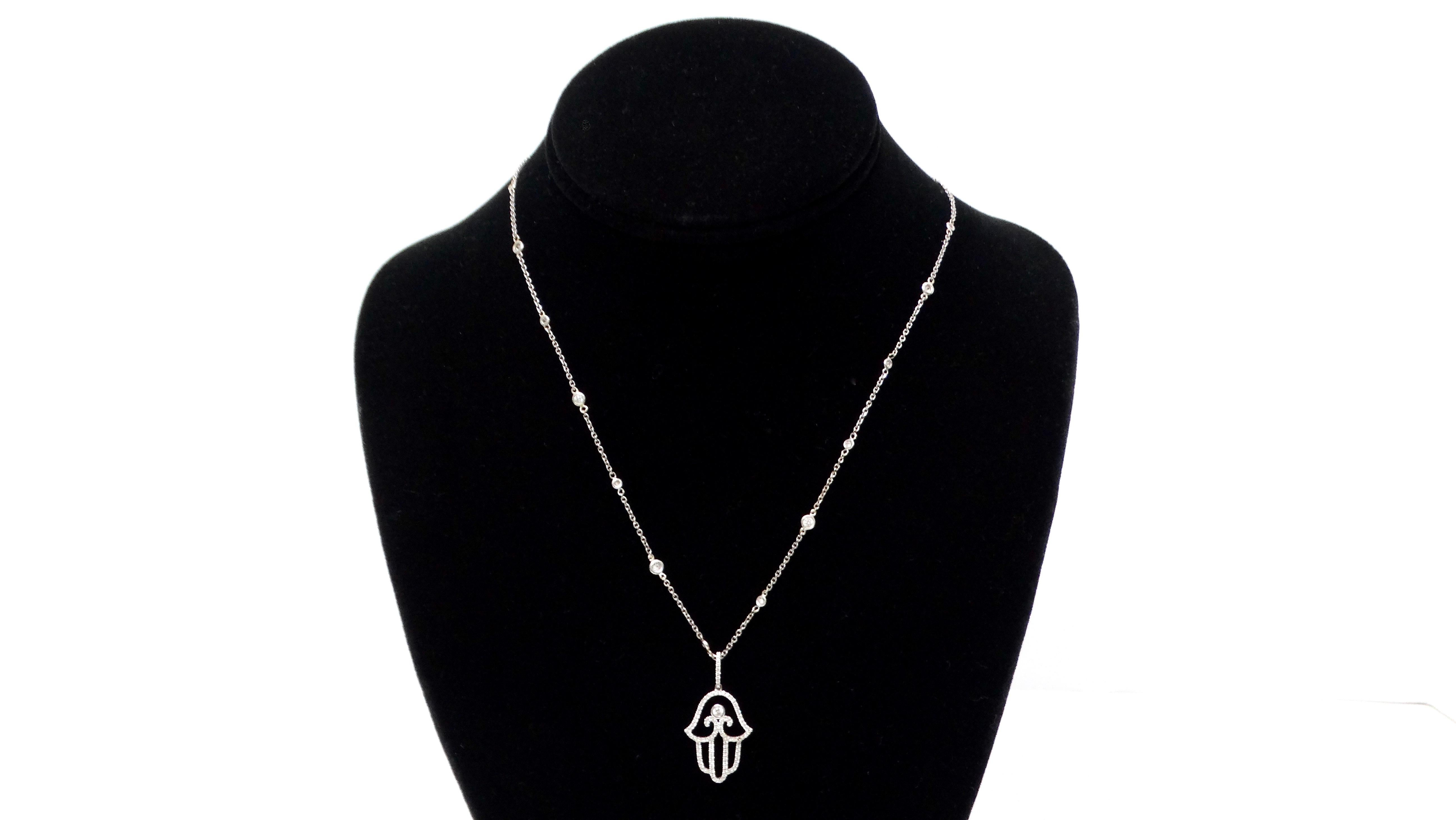 La squisita collana con ciondolo Hamsa in oro bianco 14k e 585 con diamanti è un gioiello straordinario che unisce eleganza, spiritualità e squisita maestria. Il simbolo dell'Hamsa, che si ritiene protegga e porti fortuna, è splendidamente