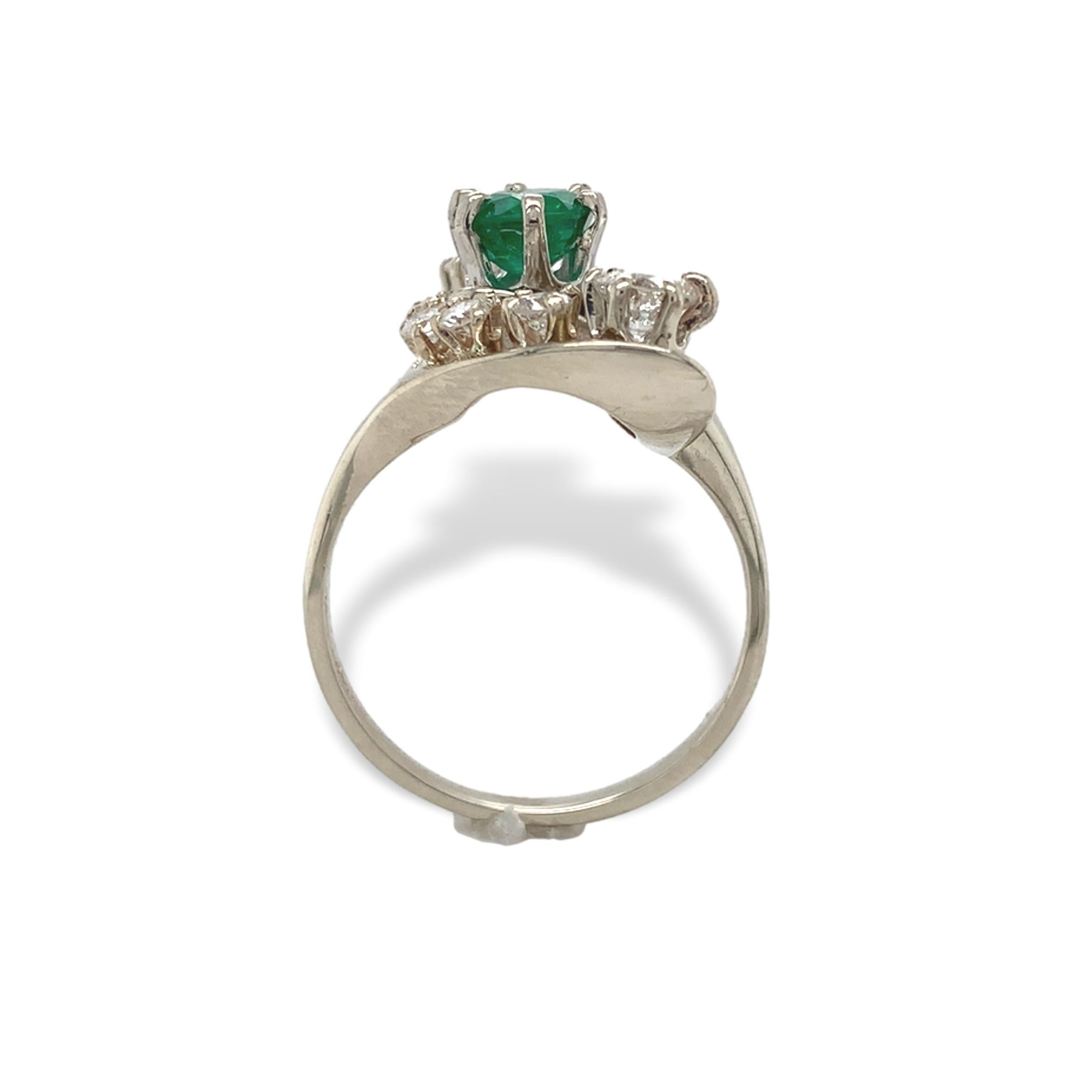 14K white gold ring featuring a round emerald weighing .65cts. The genuine earth mined emerald has medium green color and measures about 5.5mm. There are 11 round diamonds (10 round brilliant cut and 1 single cut) weighing about .95cts total. The
