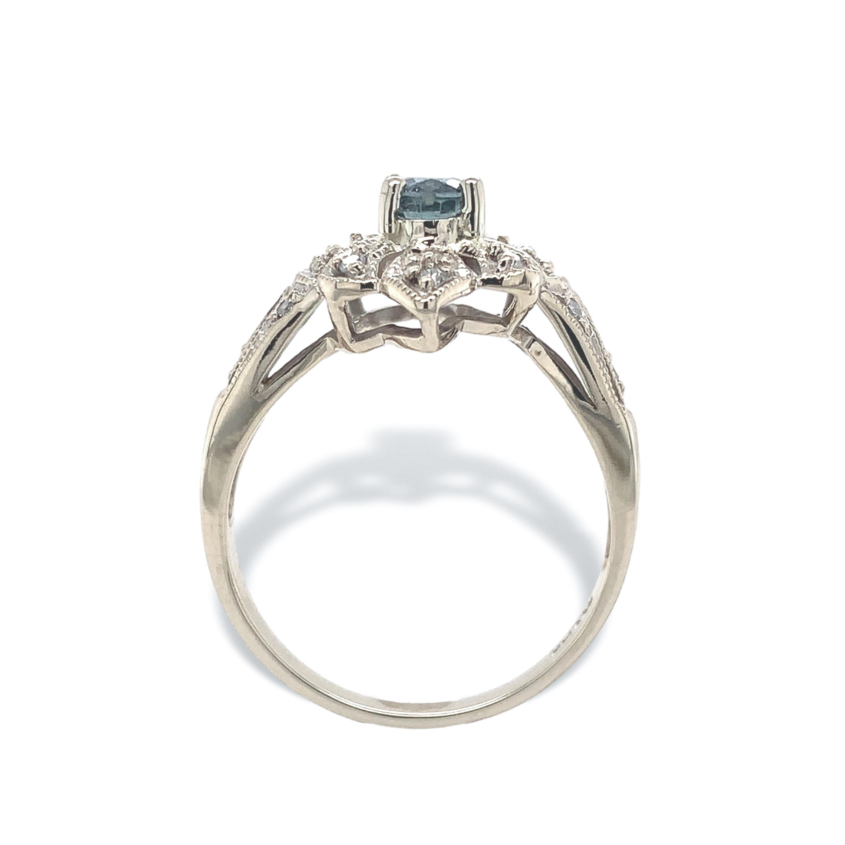 Anillo de zafiro de oro blanco de 14 quilates. El anillo lleva un auténtico zafiro azul de talla oval extraído de la tierra. Mide unos 5,1 mm x 4,2 mm y pesa 0,67cts. El zafiro es de color azul grisáceo medio, se extrae en Montana y es natural sin