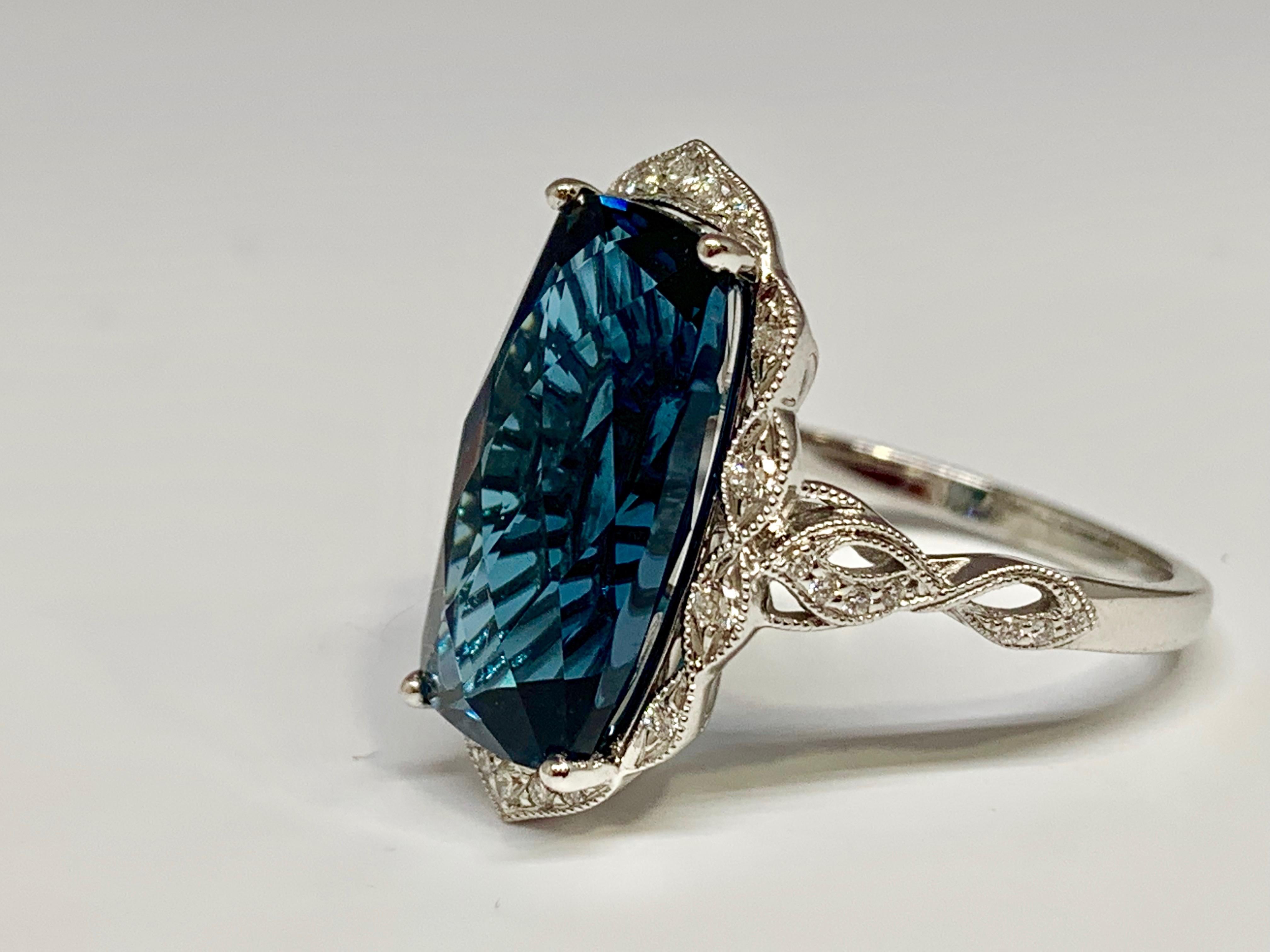 This gorgeous cocktail ring from Allison-Kaufman Company holds a 6.75 carat elongated cushion cut blue topaz with checkerboard faceting. The 14K white gold mounting includes 0.15 carats of round diamonds within its vintage inspired halo. The ring is