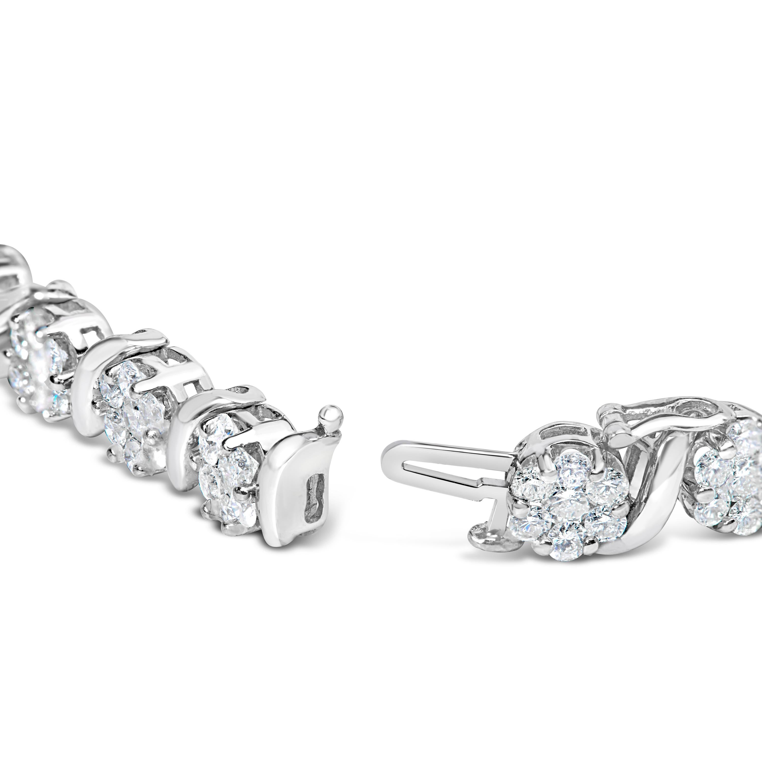 Elegant et intemporel, ce magnifique bracelet de tennis en or blanc 14 carats présente un poids total de 7,38 carats de diamants blancs ronds naturels. Le bracelet de tennis est composé de maillons articulés alternant des swooshes en forme de S et
