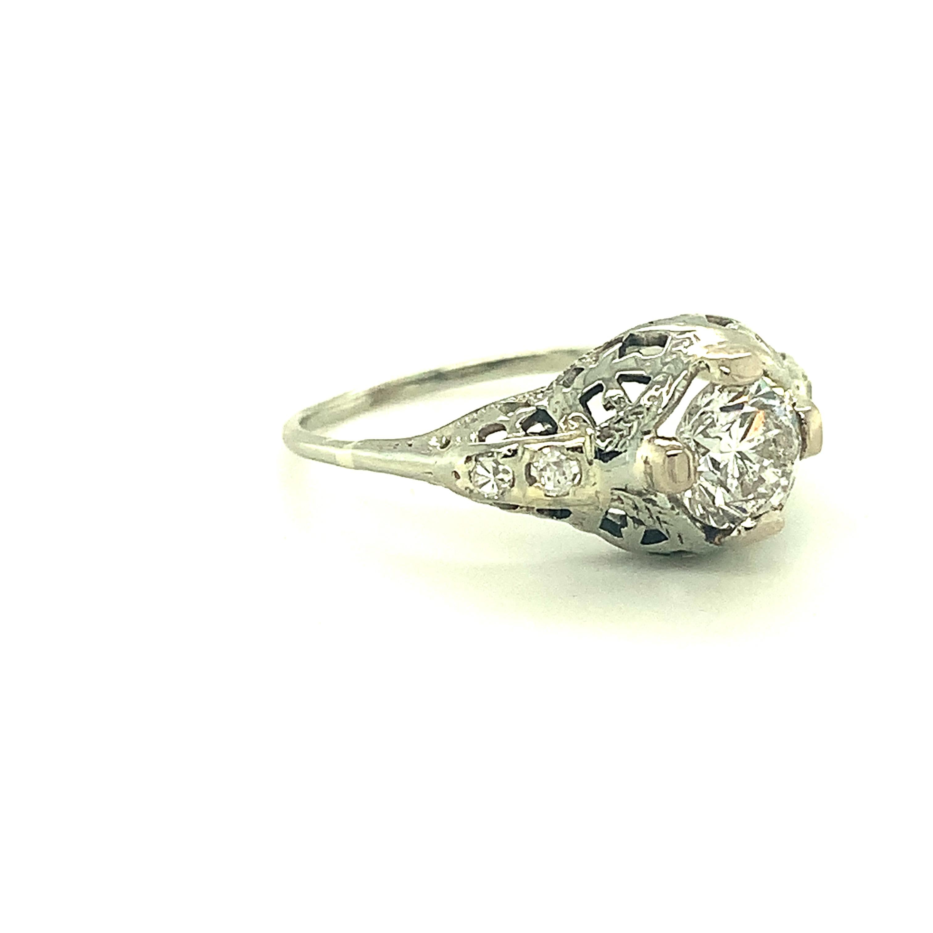 Art Deco 14K white gold filigree ring featuring a round brilliant cut diamond weighing .78cts. The diamond measures  5.7mm. It has G-H color and I-1 clarity.  Beautifully pierced and engraved setting with 4 new prongs. There are 4 small round accent
