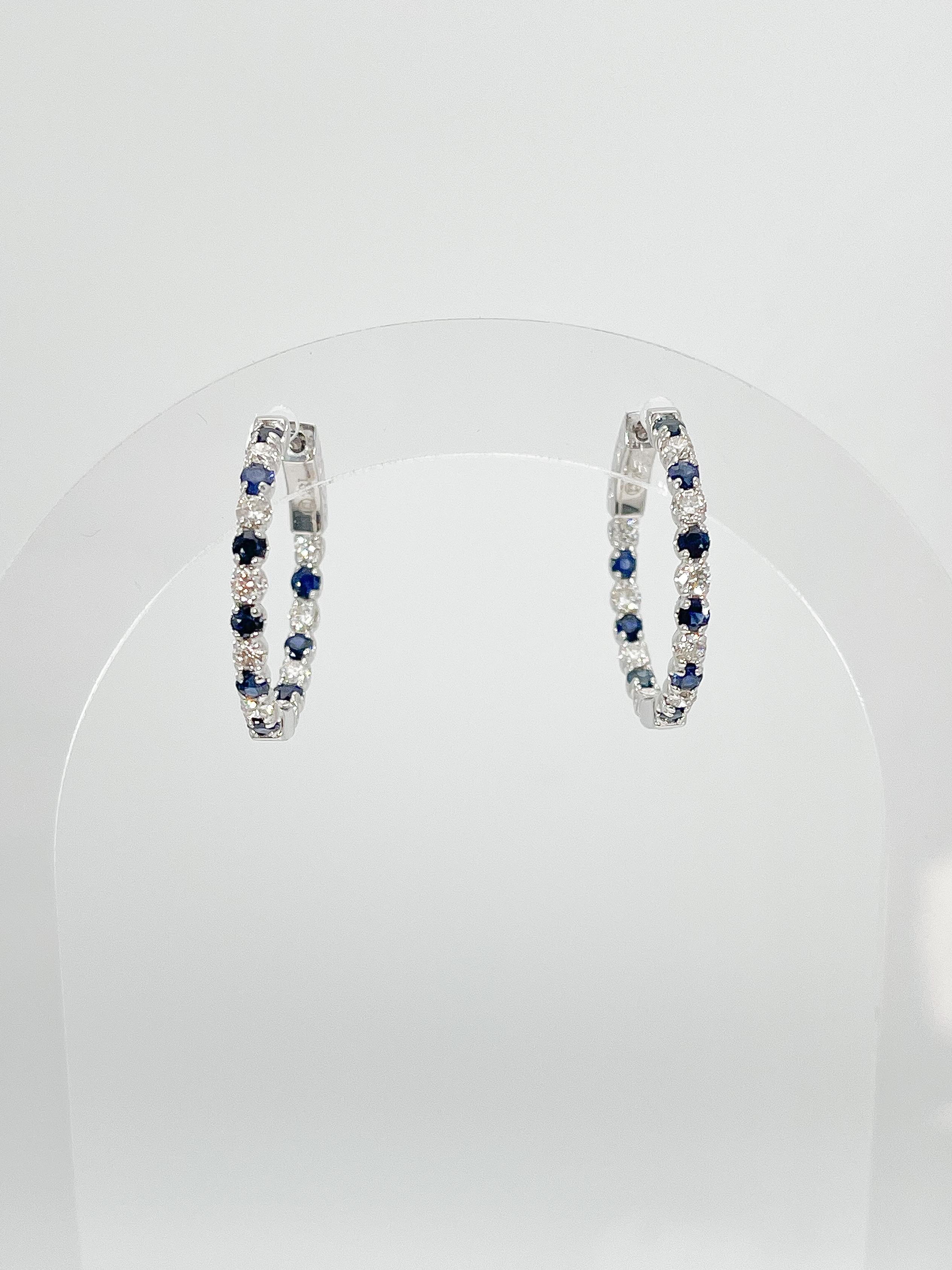 14k white gold .79 CTW diamond and 1.15 CTW sapphire hoop earrings. The stones in these earrings are all round, the measurements are 23 x 23.3 mm, and they have a total weight of 5 grams. 
