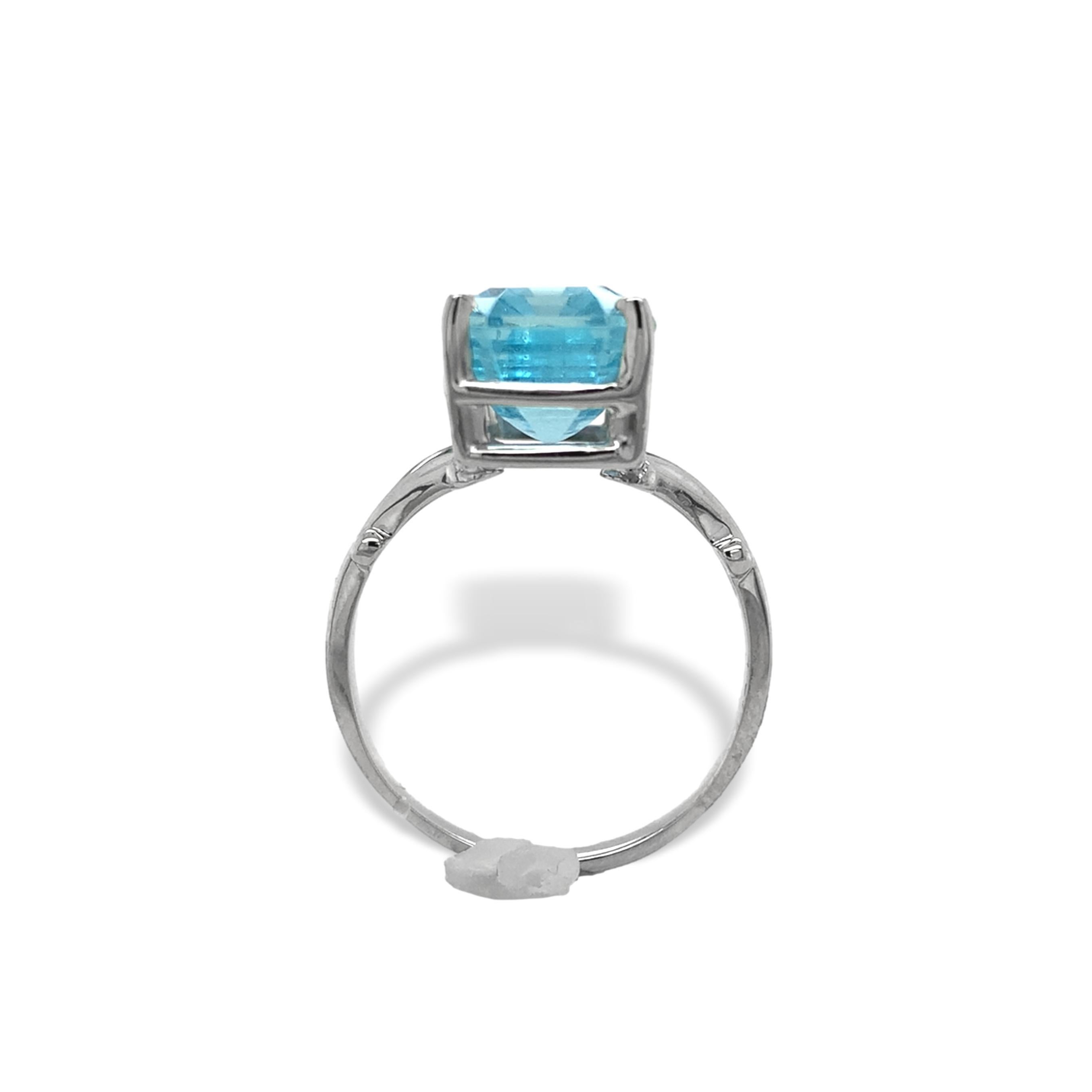 14K white gold ring featuring an emerald cut aquamarine. The aquamarine is a deeper color than normally seen, more of a Santa Maria color, light sky blue. There are some wispy natural inclusions. The aqua is a longer emerald cut measuring about