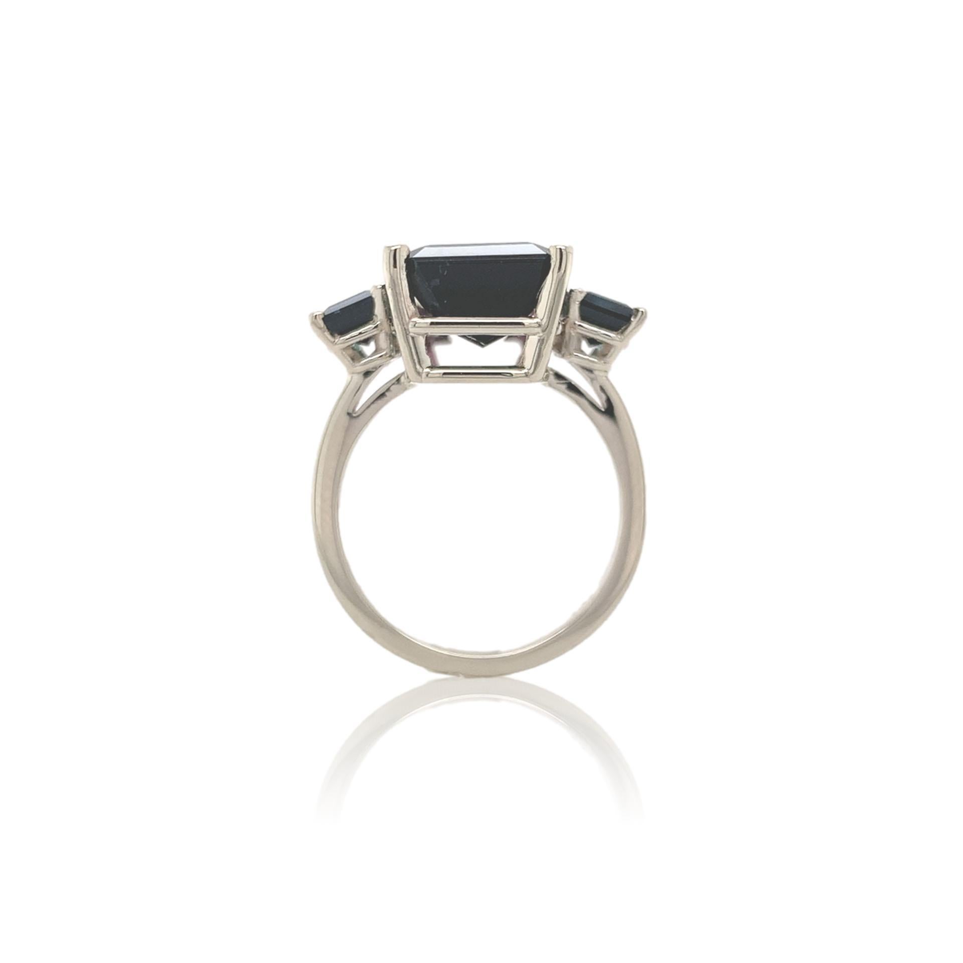 A 14K white gold ring featuring a bi-color watermelon tourmaline weighing 8.07 carats. The tourmaline has dark moody color from teal blue-green to pinkish-purple. The tourmaline is an emerald cut and measures about 14.6mm x 9.7mm. There are 2