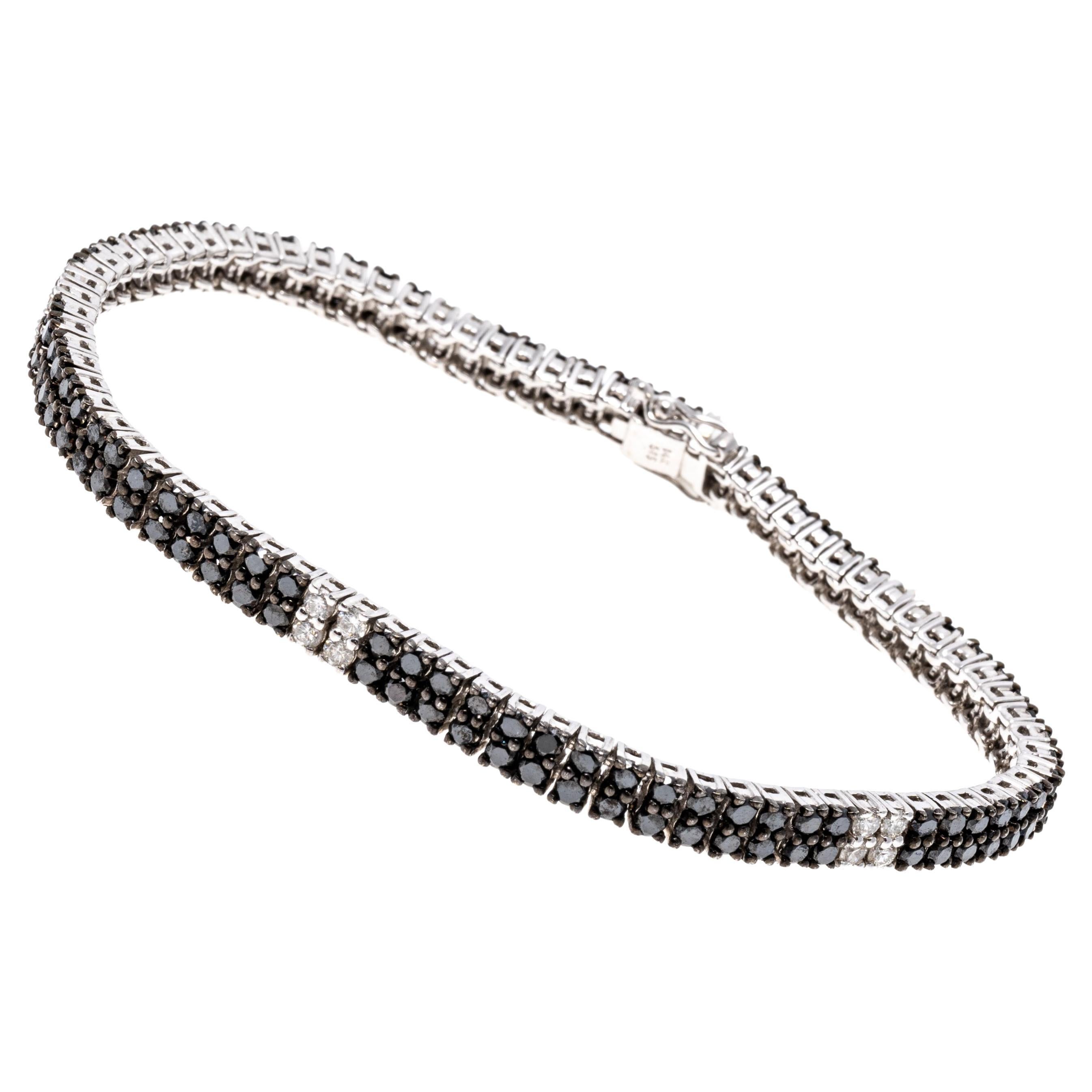 14k white gold bracelet. This amazing bracelet is a two row line style, featuring a field of round faceted black diamonds, punctuated with five stations of white faceted diamonds. The total diamond weight for the bracelet is 5.71 TCW, all of the
