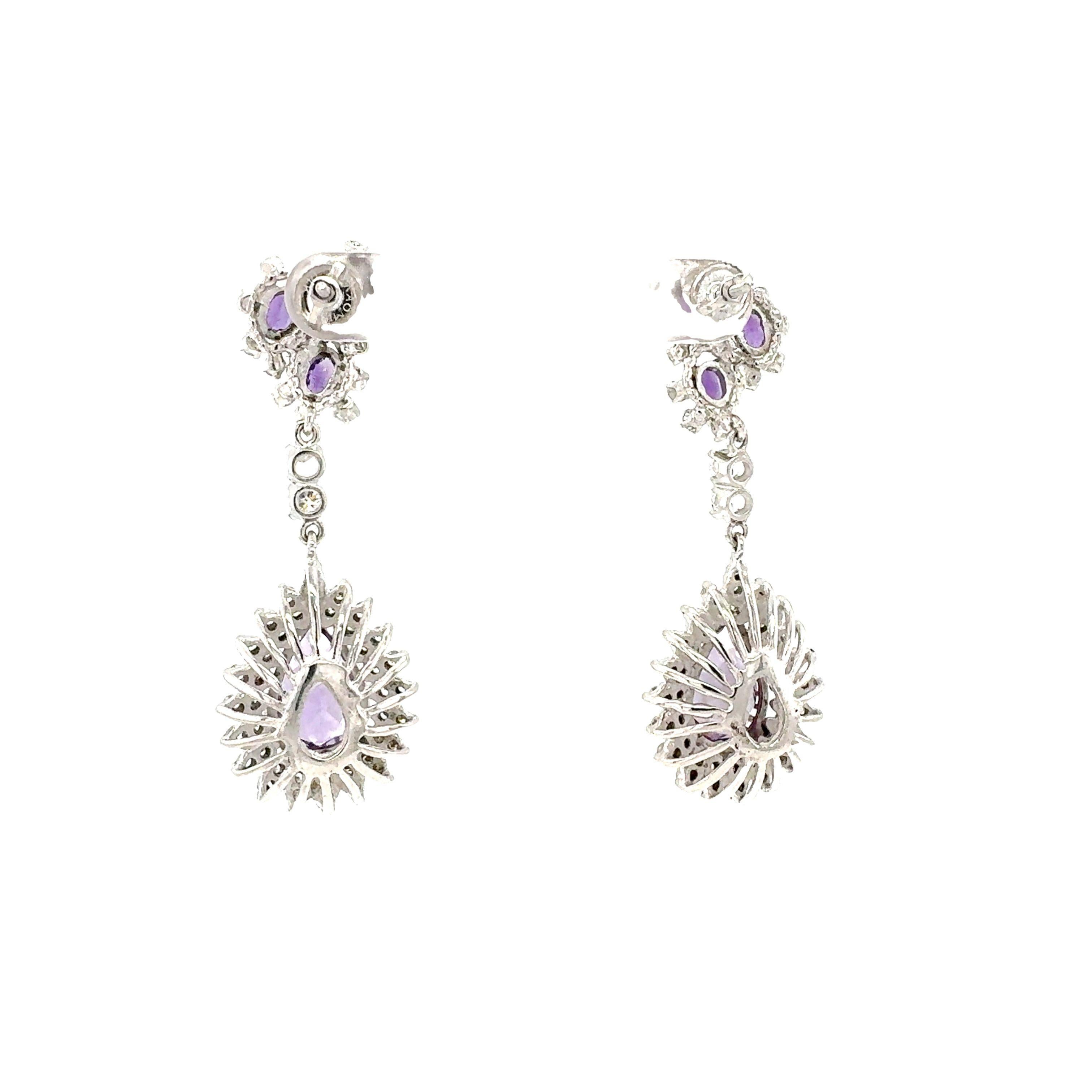This exquisite pair of mid-century dangle earrings in 14K white gold features a captivating combination of amethysts and diamonds, embodying the elegance of the 1950s. The earrings showcase a total of 8 pear and oval-cut amethysts, weighing