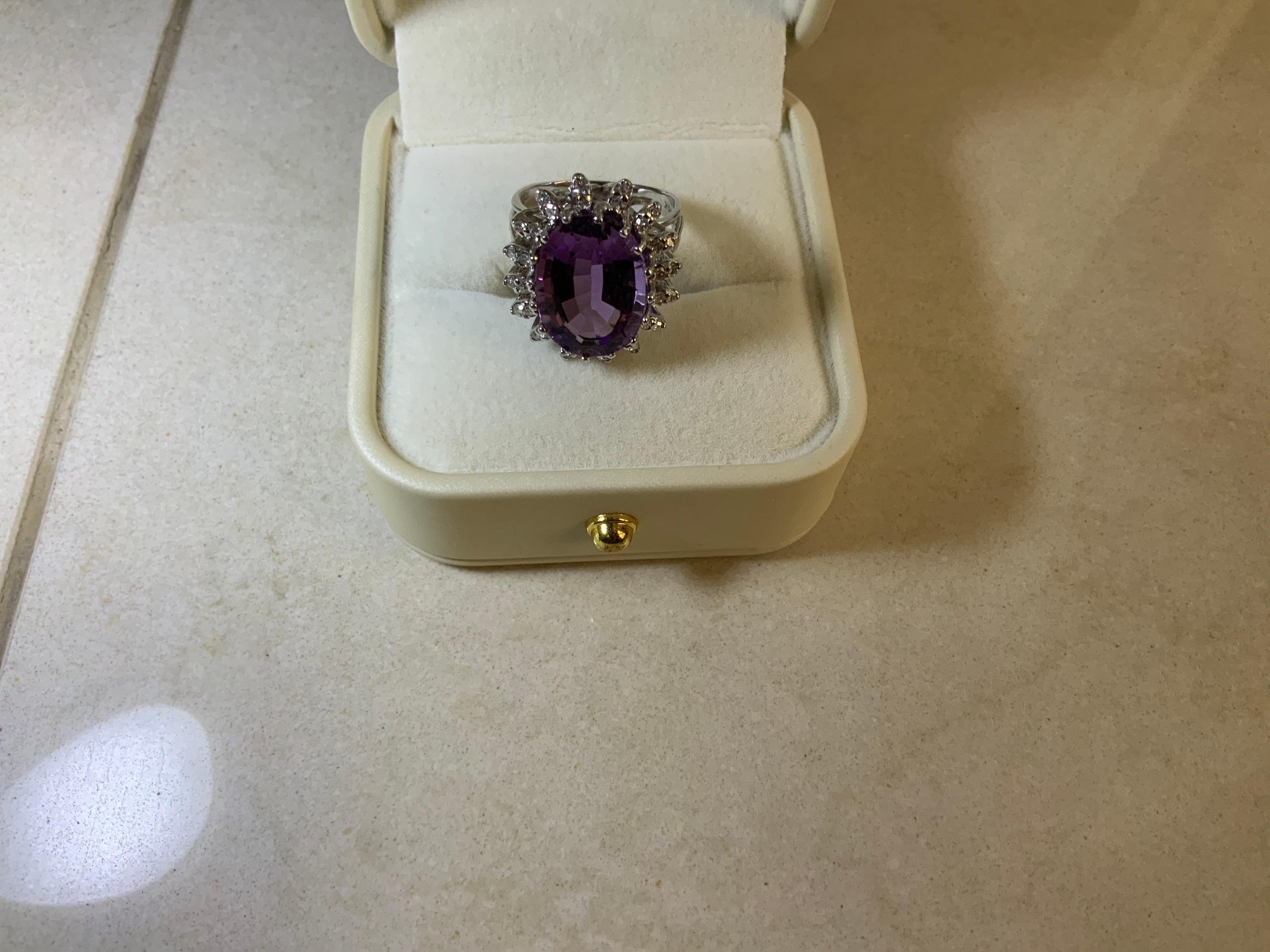 Il s'agit d'une bague en or blanc 14K avec améthyste et diamant. Whiting représente une grande améthyste ovale pesant 8,08 carats montée en or blanc 14 carats en serti clos, rehaussée d'un halo d'améthyste.  diamants de taille brillant pesant 0,32