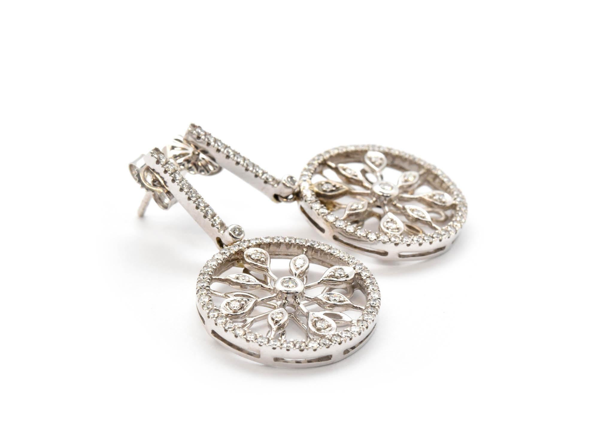 These fun earrings are made in solid 14k white gold, and each earring features a diamond circle hanging from a straight diamond bar. The diamonds have a total weight of 0.64ct, and they are graded G-H in color and SI in clarity. The earrings measure