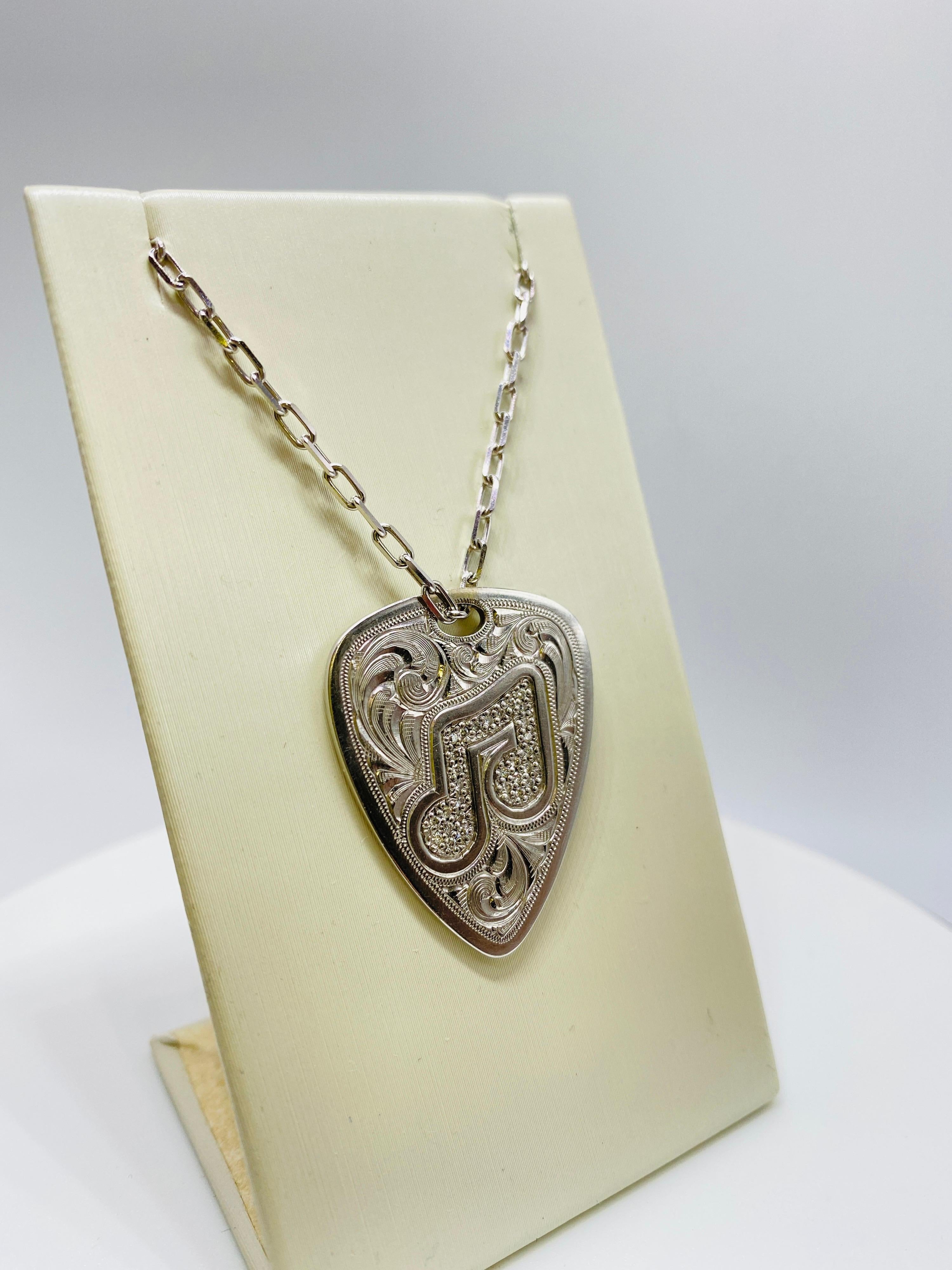 14K white gold guitar pick-shaped pendant with 29= 0.16 cute round brilliant cut diamonds. Height= 30 mm, width = 20 mm. Chain not included.