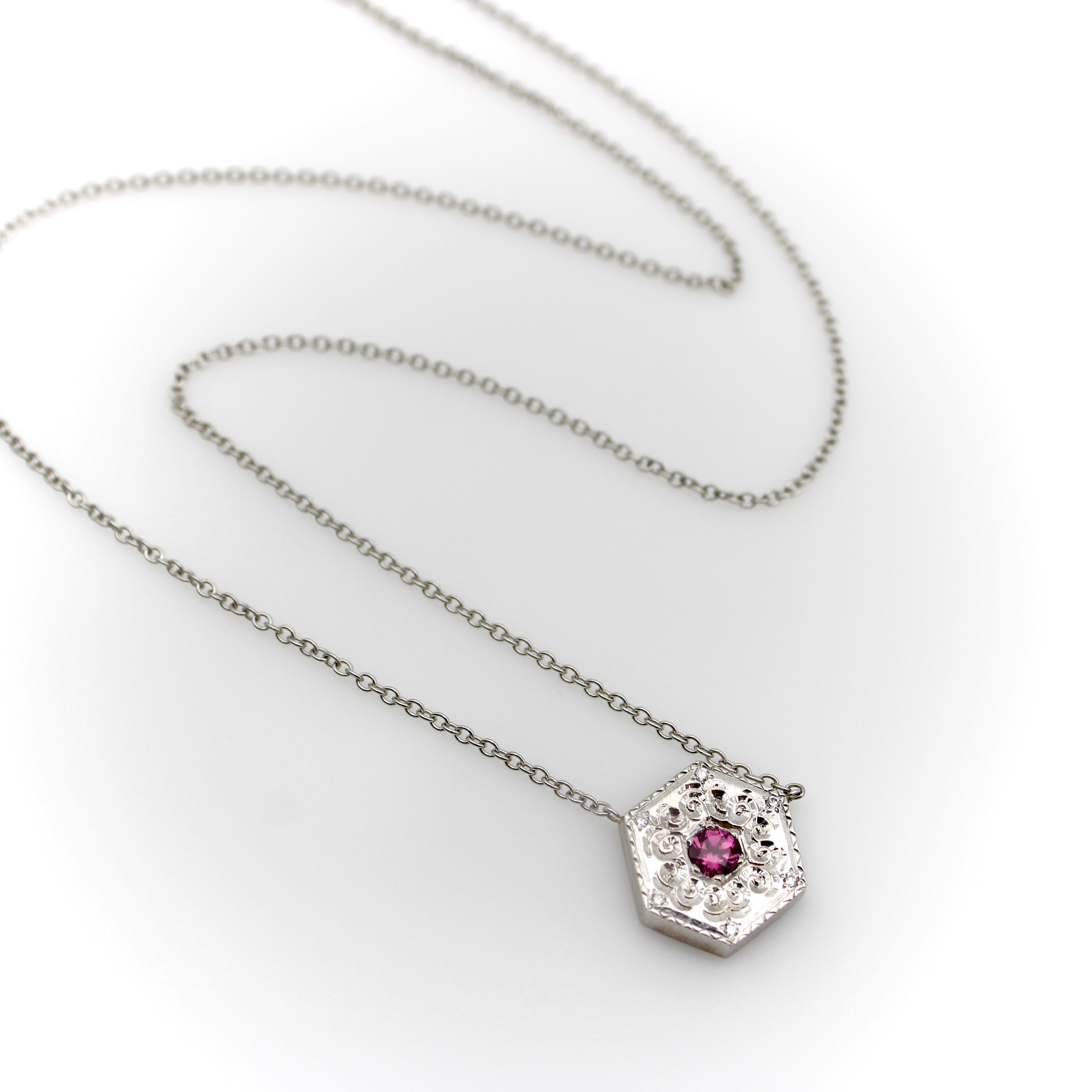 The 14k white gold medallion necklace is a one-of-a-kind piece, hand-engraved by Master Jeweler Michael von Krenner. It its center, a pink tourmaline sparkles against the white gold backdrop. The stone is bead set, surrounded by a motif of