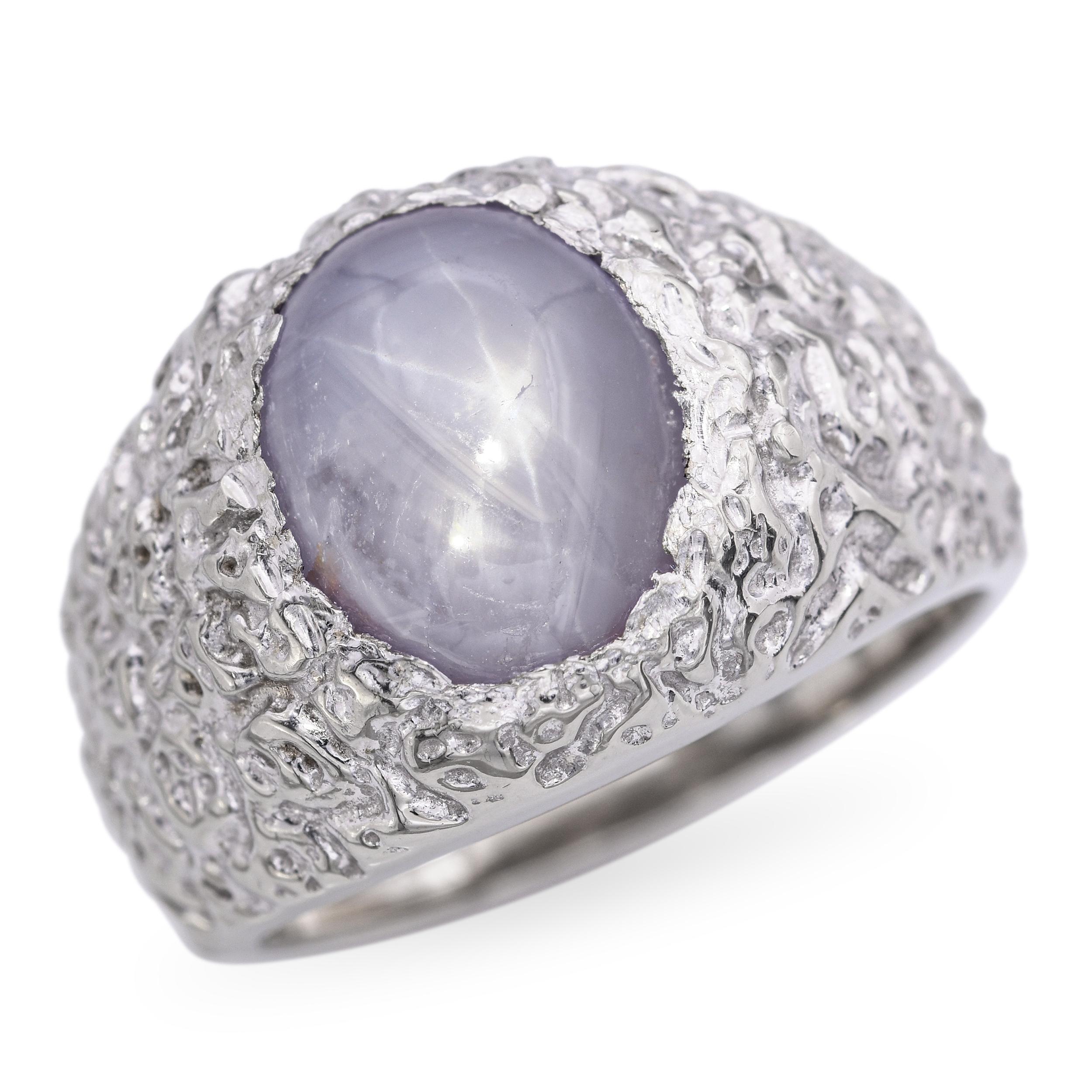 Dieser einzigartige Ring aus 14-karätigem Weißgold zeigt einen faszinierenden Sternsaphir mit einem starken, zentrierten Asterismus, der im Licht tanzt. Der Edelstein ist in eine Lünette gefasst, die ihm ein schlankes, modernes Profil verleiht und