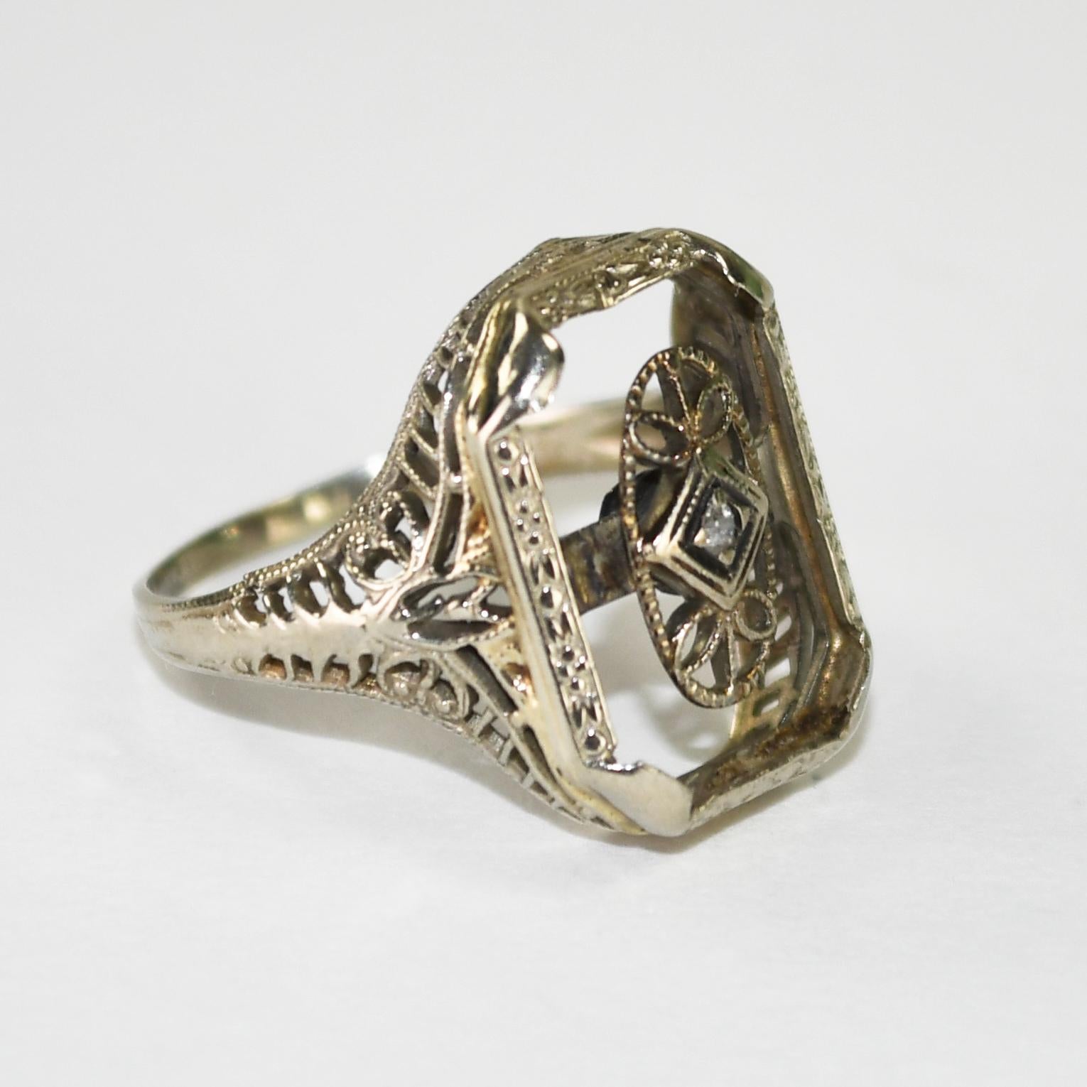 Anillo art decó antiguo de oro blanco de 14 quilates para mujer.
Prueba 58% de oro con un analizador de metales XRF y pesa 2,6 gramos.
Hay una pieza móvil en la parte superior central del anillo con un pequeño diamante astillado.
Hay un atractivo