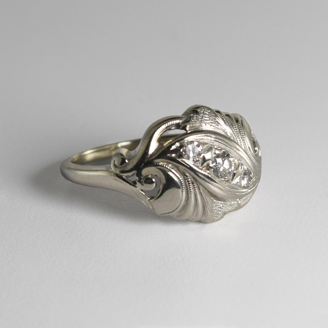 This gorgeous, antique 14 karat white gold cocktail-style ring weighs 3.90 grams.
It contains three round brilliant diamonds mounted in a pave setting, with a carat weight of 0.10.
The ring measures 12mm in width and is a size 7.
