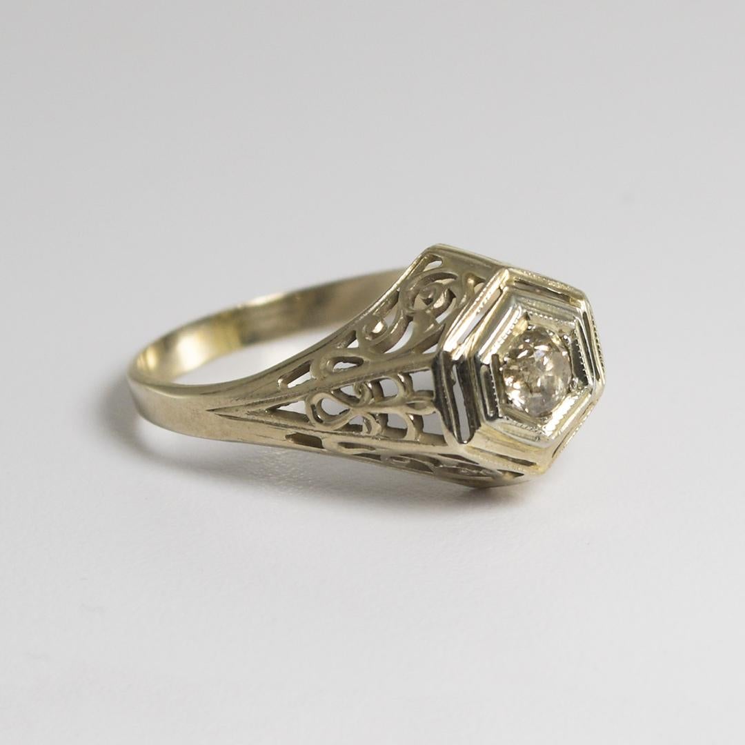Ladies' antique white gold and diamond ring.
The ring is stamped 14k and weighs 2.2 grams.
Attractive open metal work on the sides of the ring.
The diamond is an old-Euro cut, champagne color, i2 clarity, 0.20 carats.
Ring size is 6 3/4 and can be