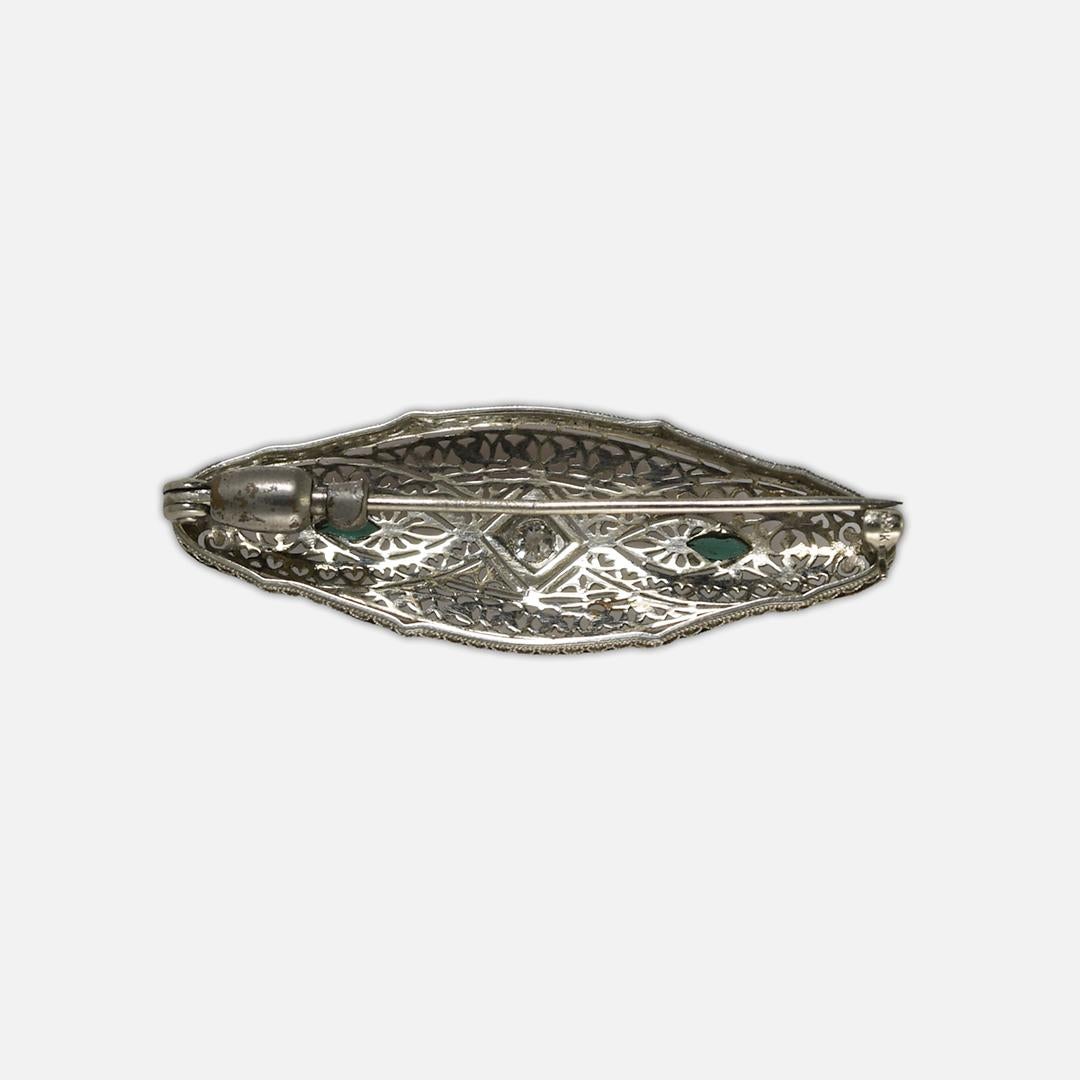 Antique diamond brooch in 14k white gold.
Stamped 14k and weighs 4.2 grams.
Beautiful open metalwork.
The diamond is an old-euro cut, H to I color, VS clarity.
There are two green glass stones on the sides.
Measures 1 3/4 by 5/8 inches. Excellent