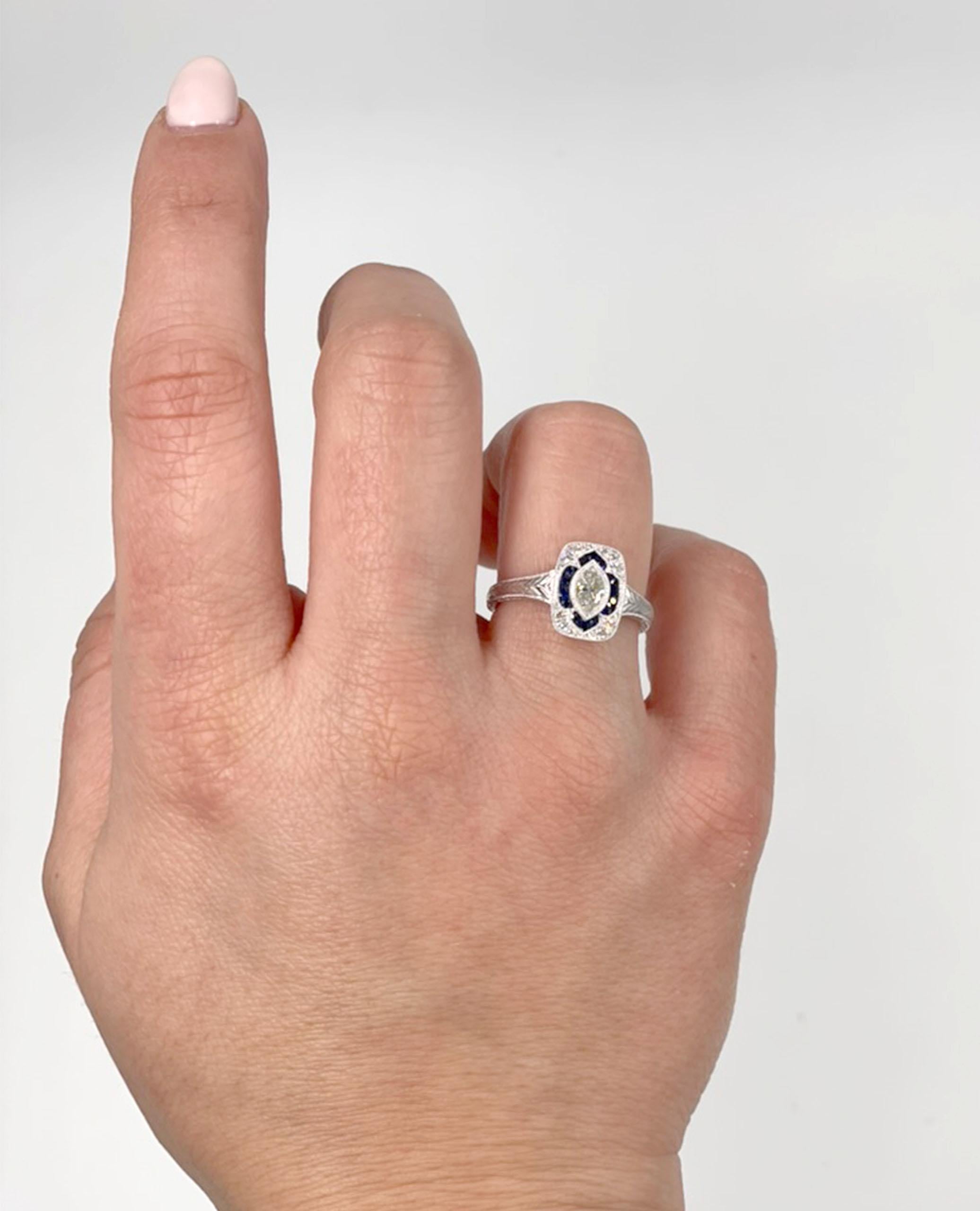 Bague en or blanc 14K d'inspiration antique avec anneau gravé.  La bague est ornée de 12 diamants ronds à facettes d'un poids total de 0,07 carat, de 14 saphirs bleus ronds à facettes d'un poids total de 0,20 carat et d'un diamant marquis d'un poids