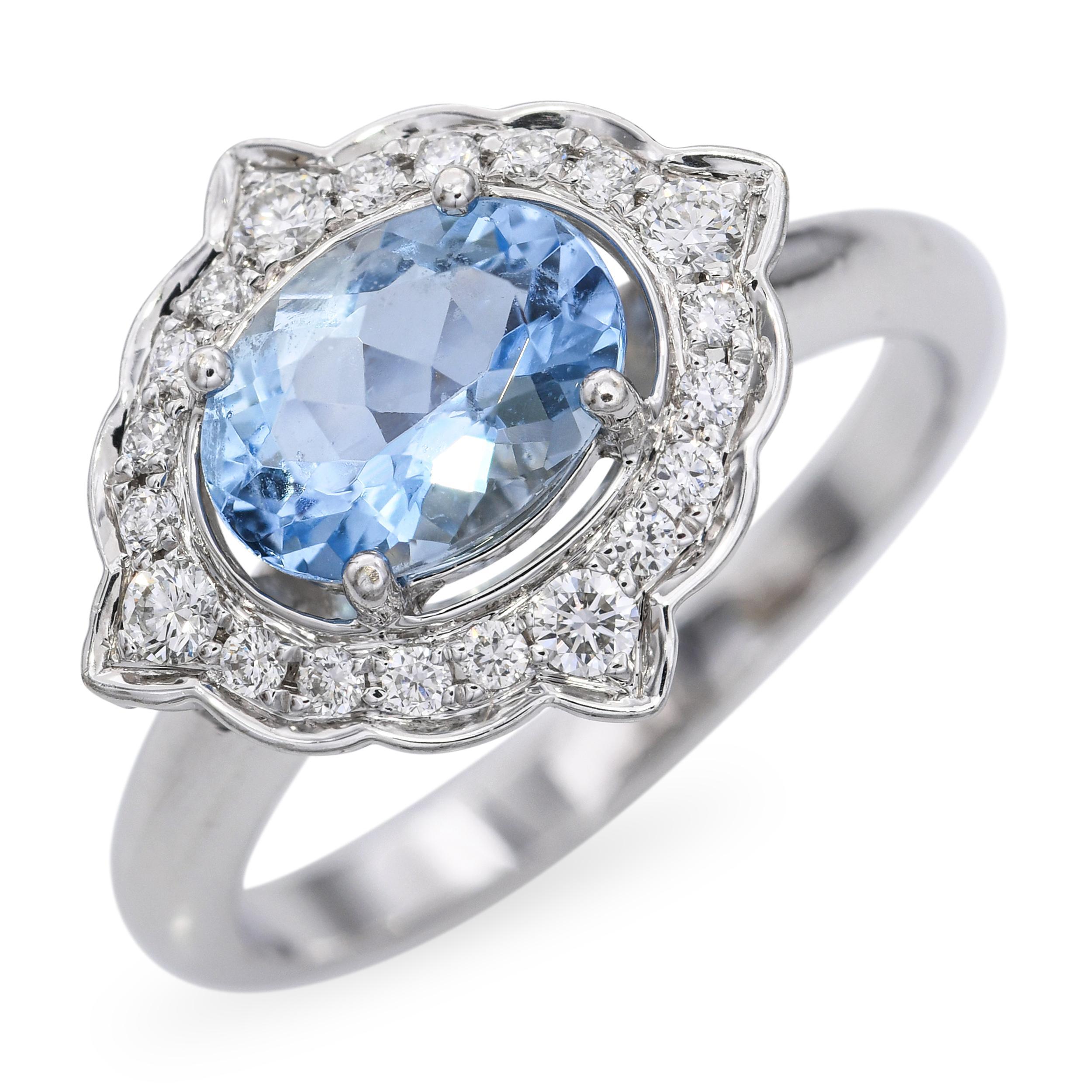 Este elegante anillo vintage está elaborado en oro blanco de 14 quilates y luce una serena aguamarina como pieza central. Alrededor de la suave gema azul hay un delicado halo de brillantes diamantes, que realzan su suave color con un brillo añadido.