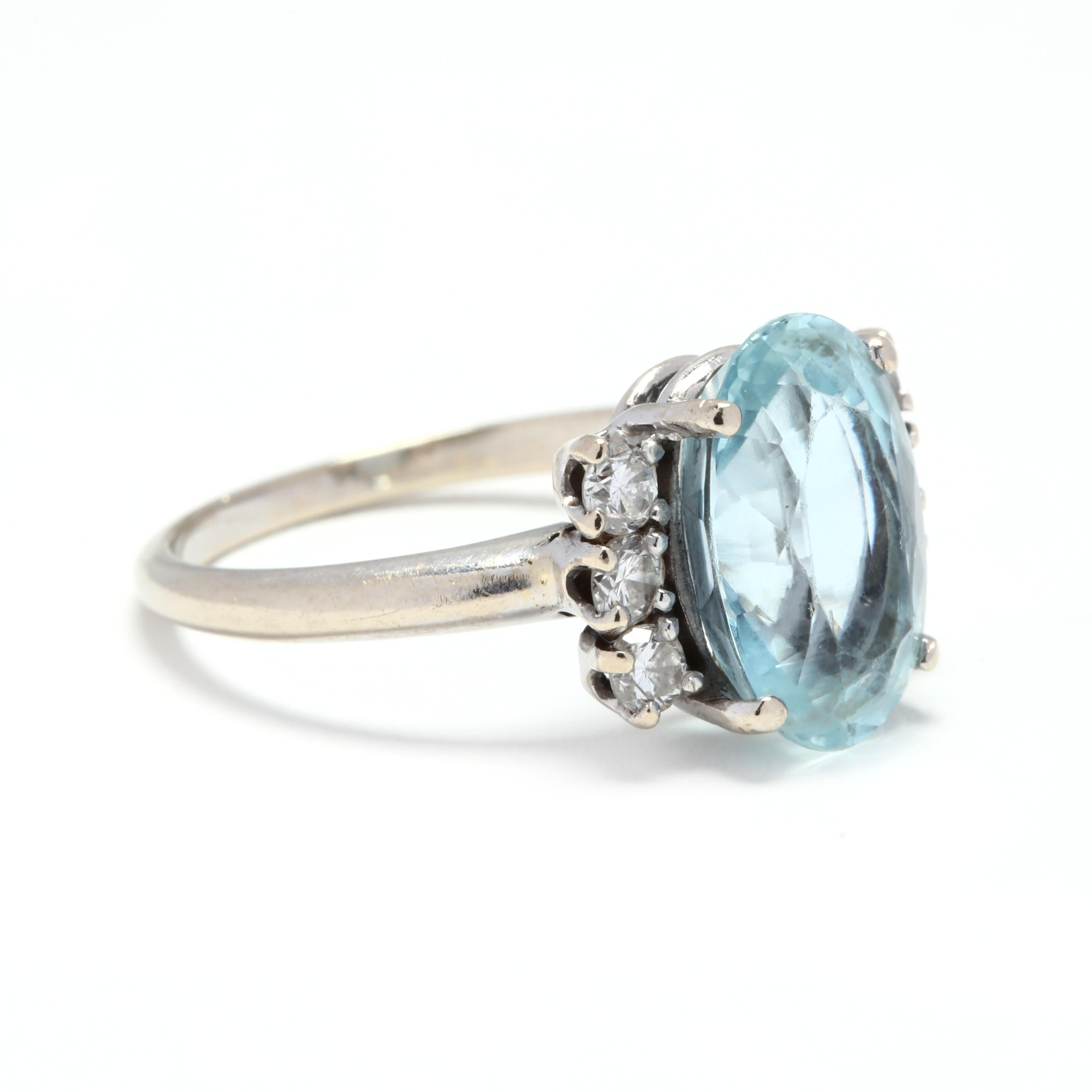 A 14 karat white gold, aquamarine and diamond cocktail ring. This ring features a prong set, oval cut aquamarine center stone weighing approximately 3.65 carats with three full cut round diamonds on either side weighing approximately .36 total