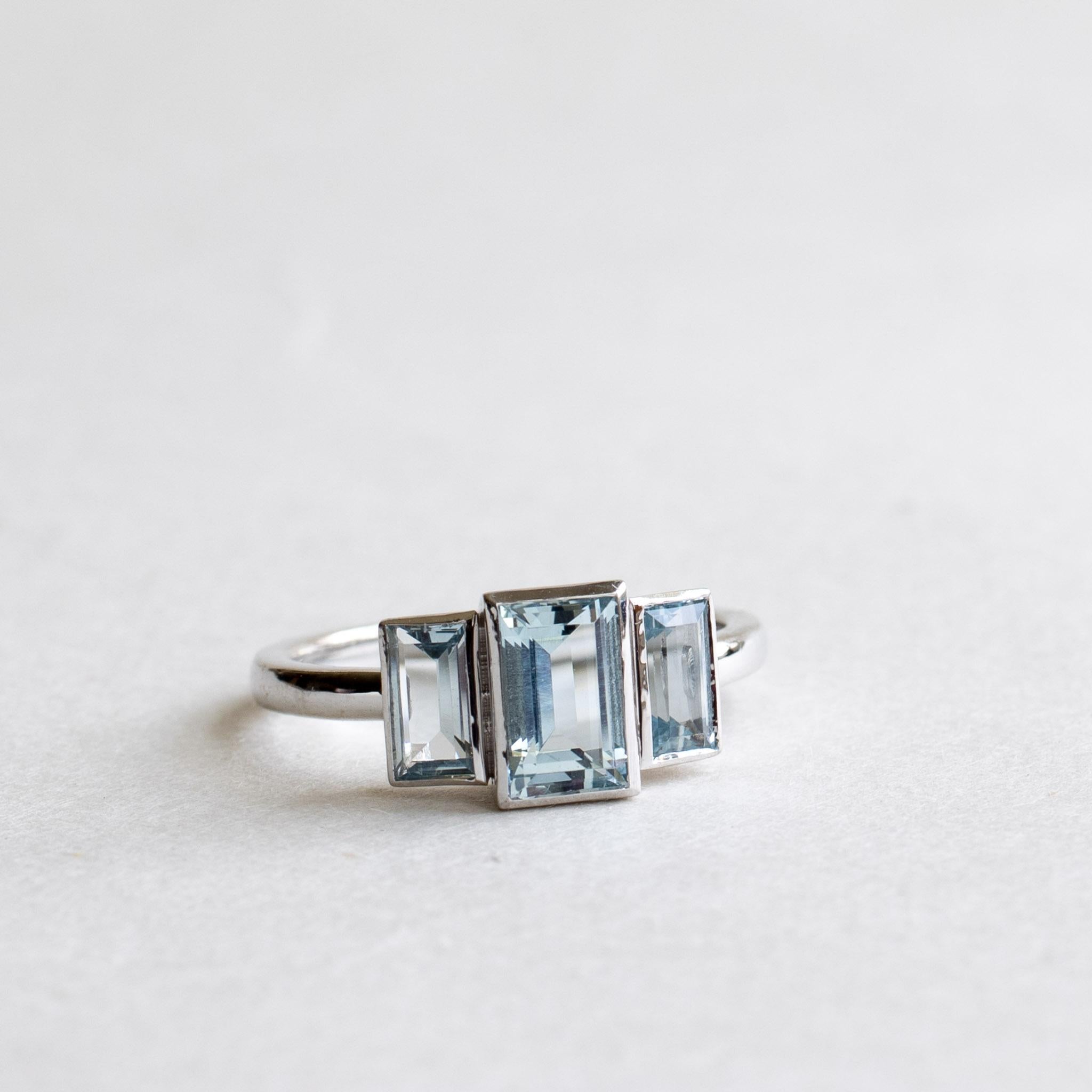 Aquamarin Baguette Trilogie Ring

Metall: 14K Weißgold
Stein: Aquamarin 
Steingröße: 4,88mm x 7,77mm Aquamarin
Seitenstein: 3,4 mm x 6 mm
Steingewicht: 1,52 Karat Gesamtgewicht
Lünette gesetzt
Breite des Bandes: ca. 2 mm x 1,65 mm