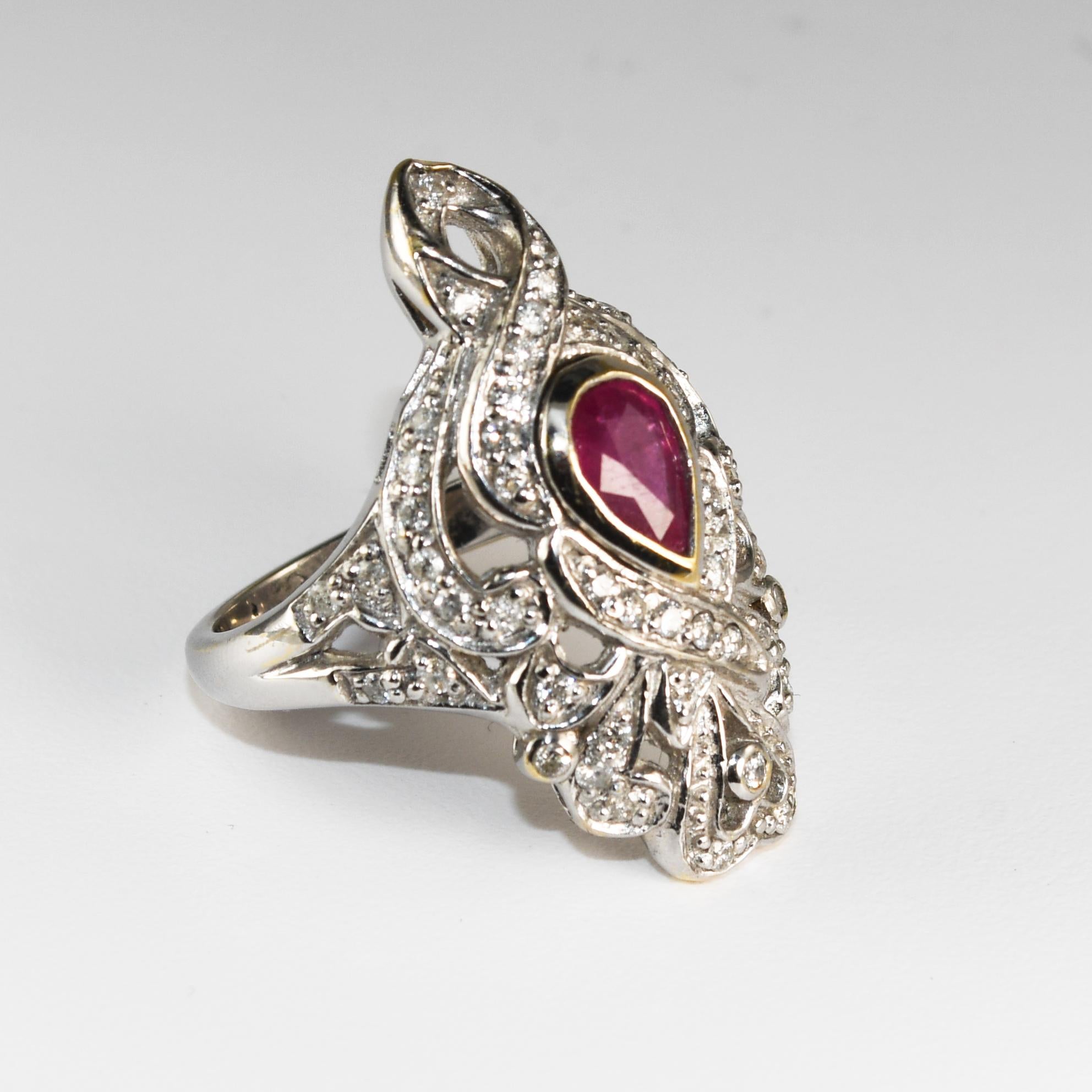 This is a 14k white gold Art Deco Ruby and Diamond ring.
The center stone is a pear-shaped 6 x 4-millimeter ruby with an approximate weight of 0.60 carats mounted in a bezel setting.
There are 50 round brilliant diamonds with a total weight of 0.50