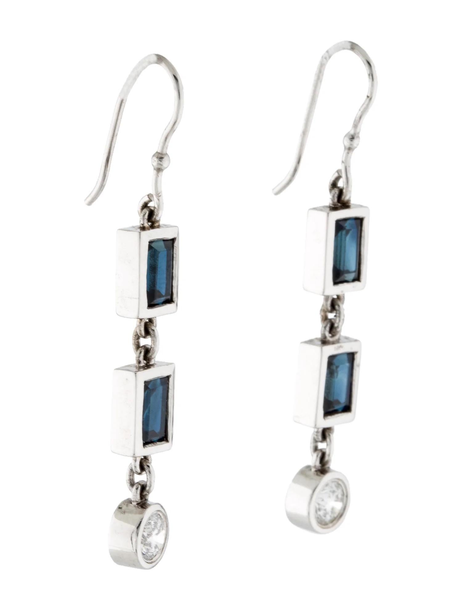 These dangle earrings are set in 14K White Gold with Four (4) Rectangular Step Cut Blue Sapphires weighing 3.31ctw and Two (2) Round Brilliant Cut Diamonds Weighing 0.67ctw. 