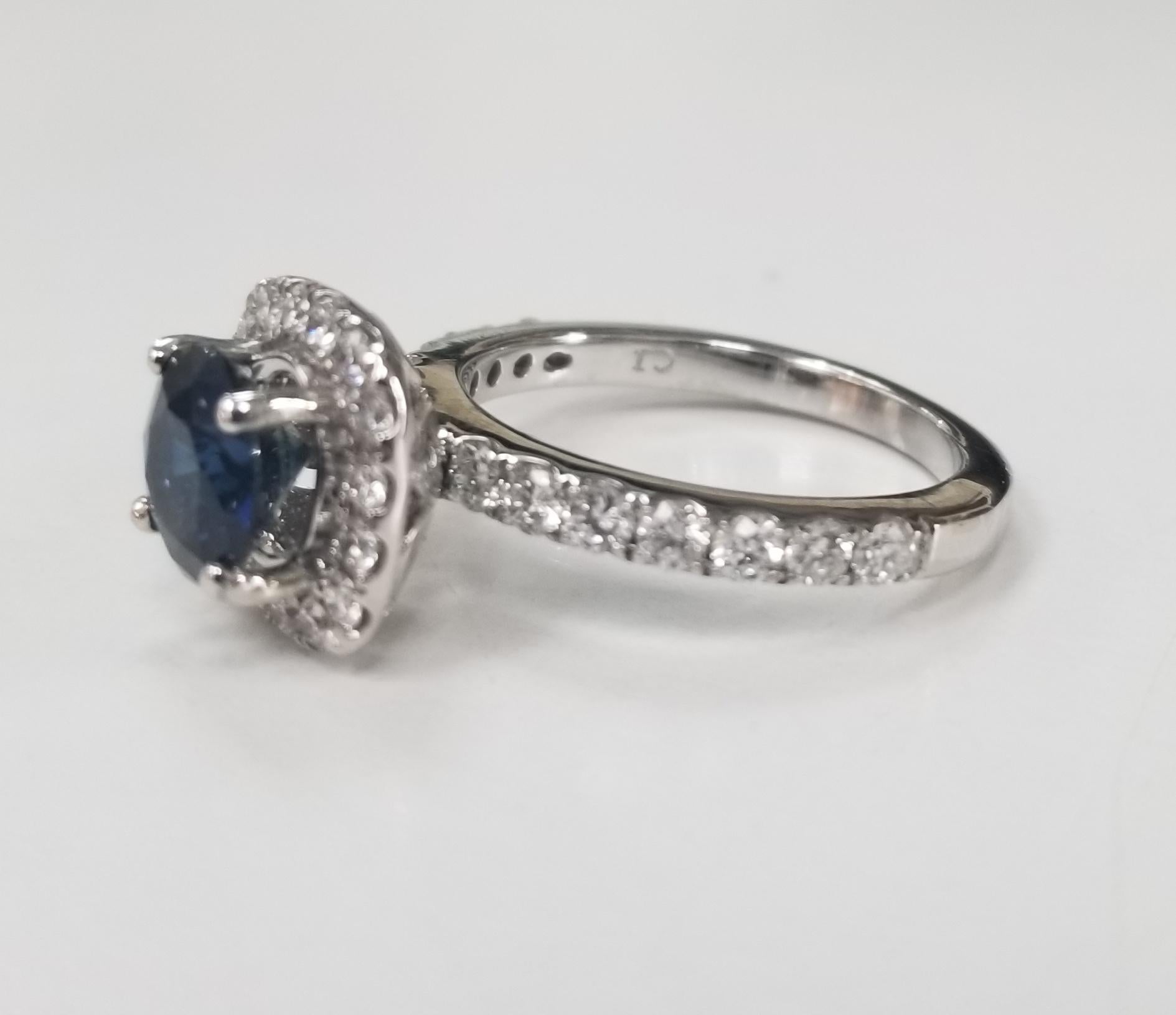 14k white gold blue sapphire and diamond halo ring, containing 1 round blue sapphire of gem quality weighing 1.50cts. and with 30 round full cut diamonds of very fine quality weighing .50pts. ring size is 6 and can be sized to fit for free.