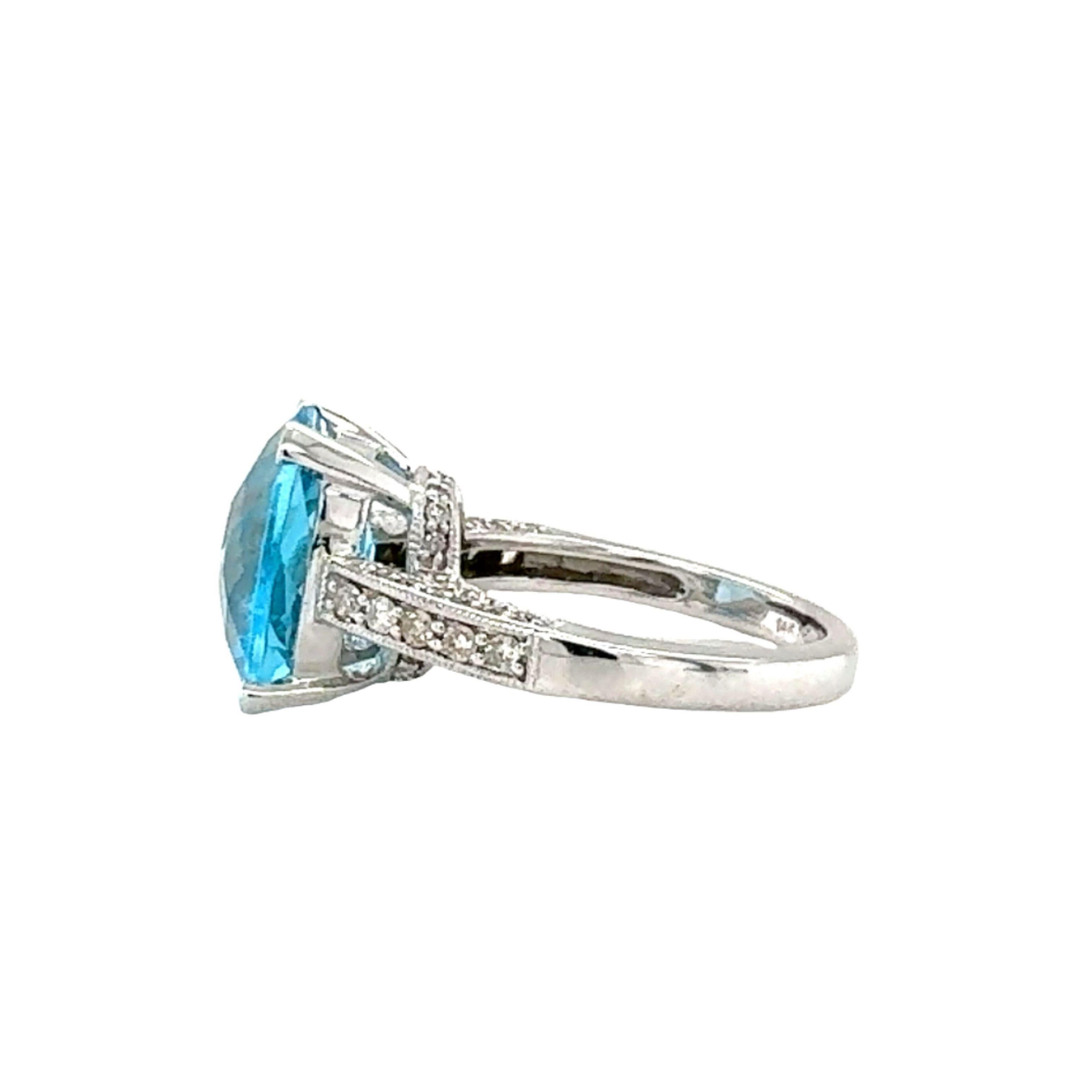 This elegant 14K white gold ring showcases a captivating 6.74-carat oval cushion-cut blue topaz at its center, held by secure prongs that beautifully display its vibrant blue hue. Surrounding the topaz are 60 pave-set round brilliant-cut diamonds,