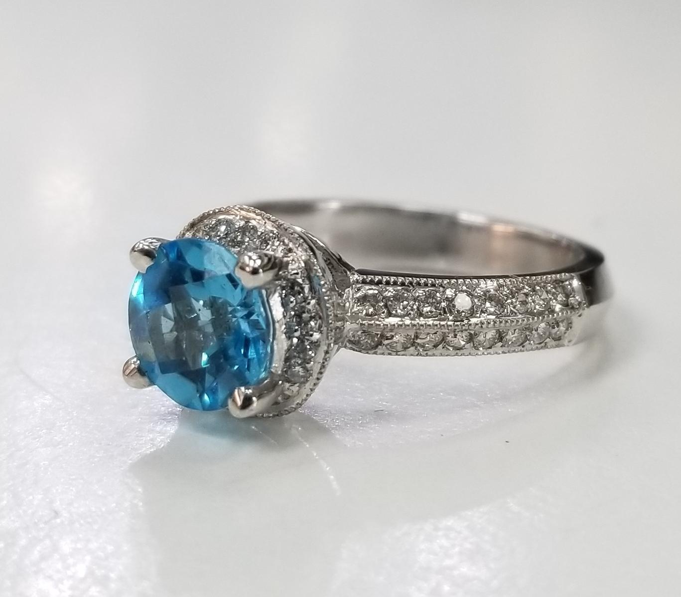 14k white gold blue topaz and diamond ring paved on knife edge, containing 1 round blue topaz of gem quality weihging .50pts. and 44 round full cut diamonds of very fine quality weighing .51pts. set on a knife edge. ring size is 5.75