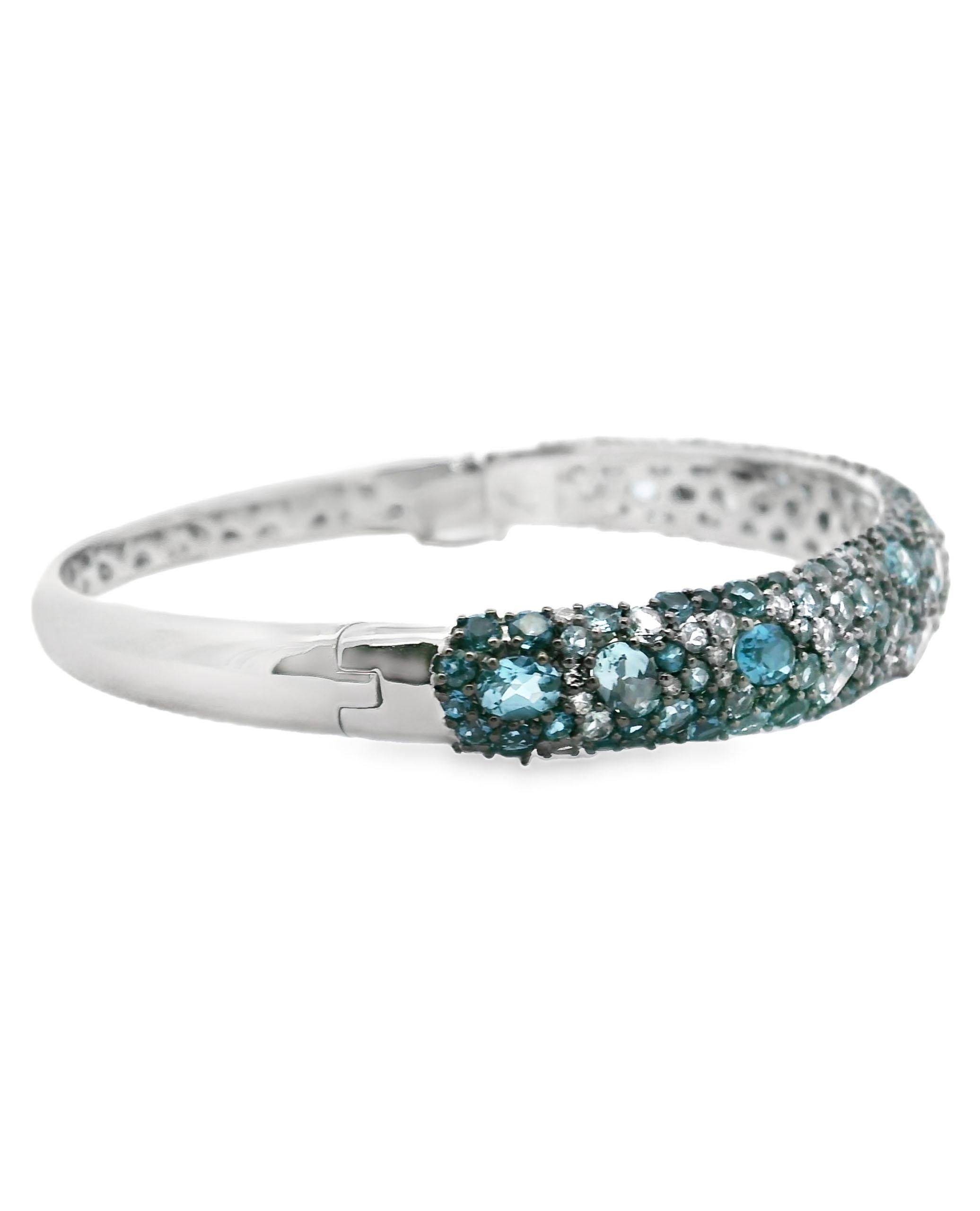 Allison Kaufman 14K white gold hinged bangle with blue topaz weighing 7.60 carats total and diamonds weighing 0.25 carats total.   

- Diamonds are G color, SI1/2 clarity.
- Hidden safety clasp.