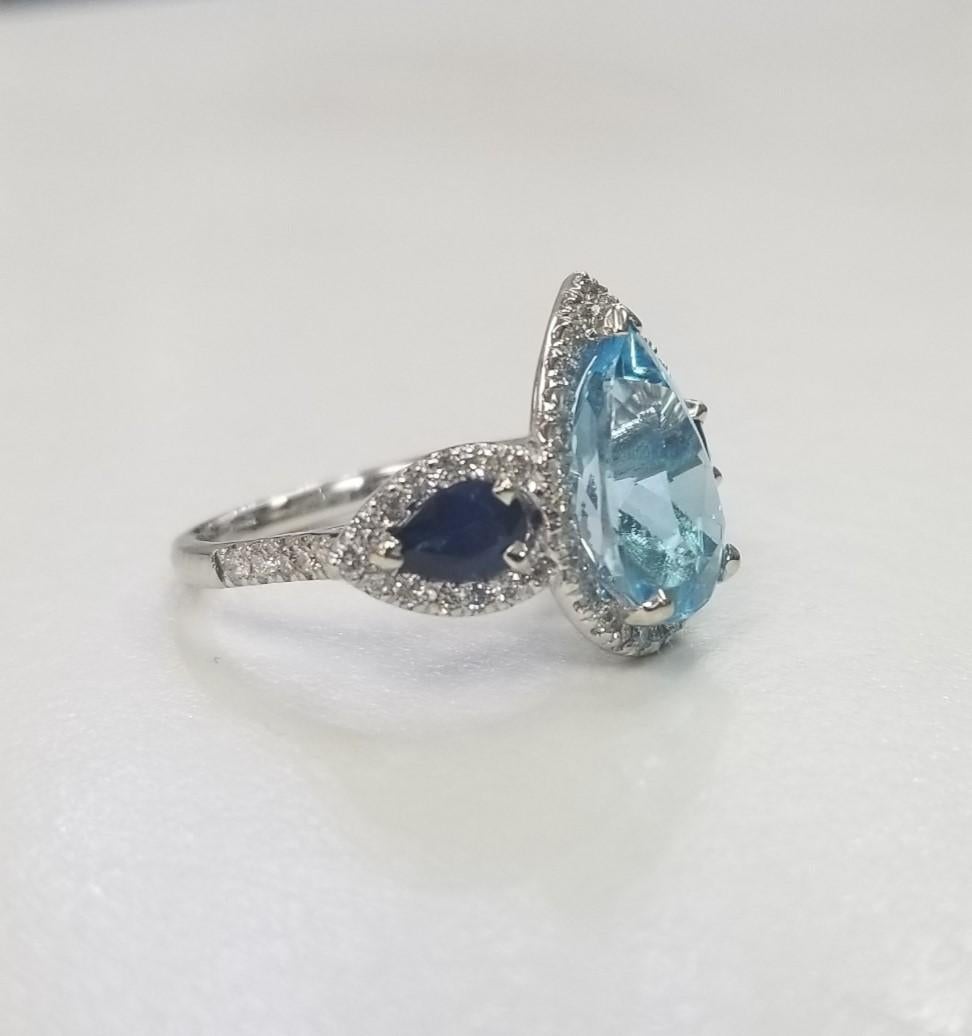  14k White Gold Blue Topaz, Blue Sapphire and diamond 3 stone halo ring
Specifications:
Total Carat Weight:  6.86cts.	
Main Stone: 	Blue Topaz Pear shape 5.07
Sizable: 	Yes

Secondary Stone: 	Blue Sapphire pear shape 1.04cts. and 62 round diamonds
