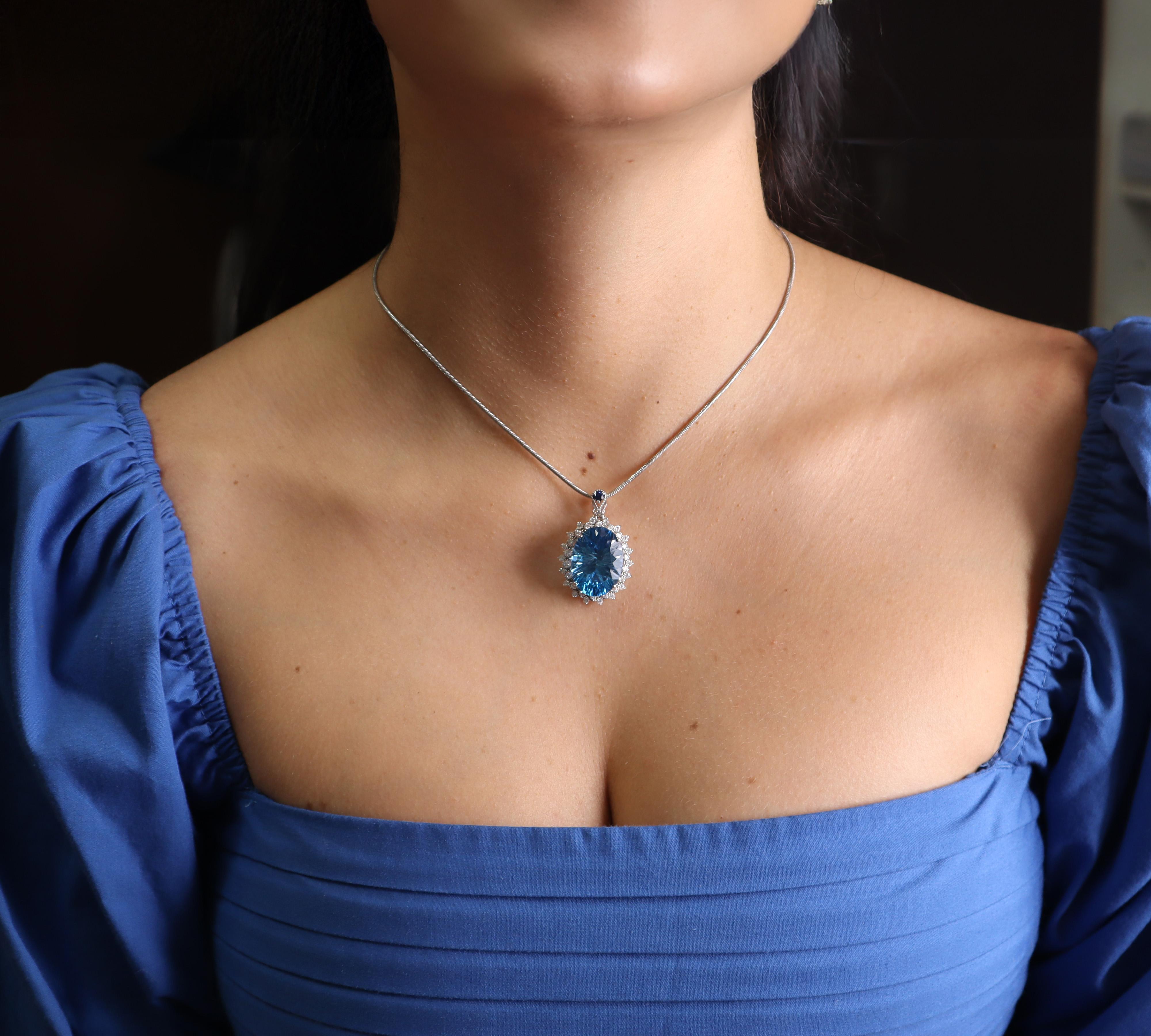 Ce superbe collier contemporain met en valeur la beauté captivante de la topaze bleue naturelle. Il est réalisé en or blanc lustré de 14kt et présente une magnifique topaze bleue de 18,00 carats comme pièce maîtresse, magnifiquement complétée par 36