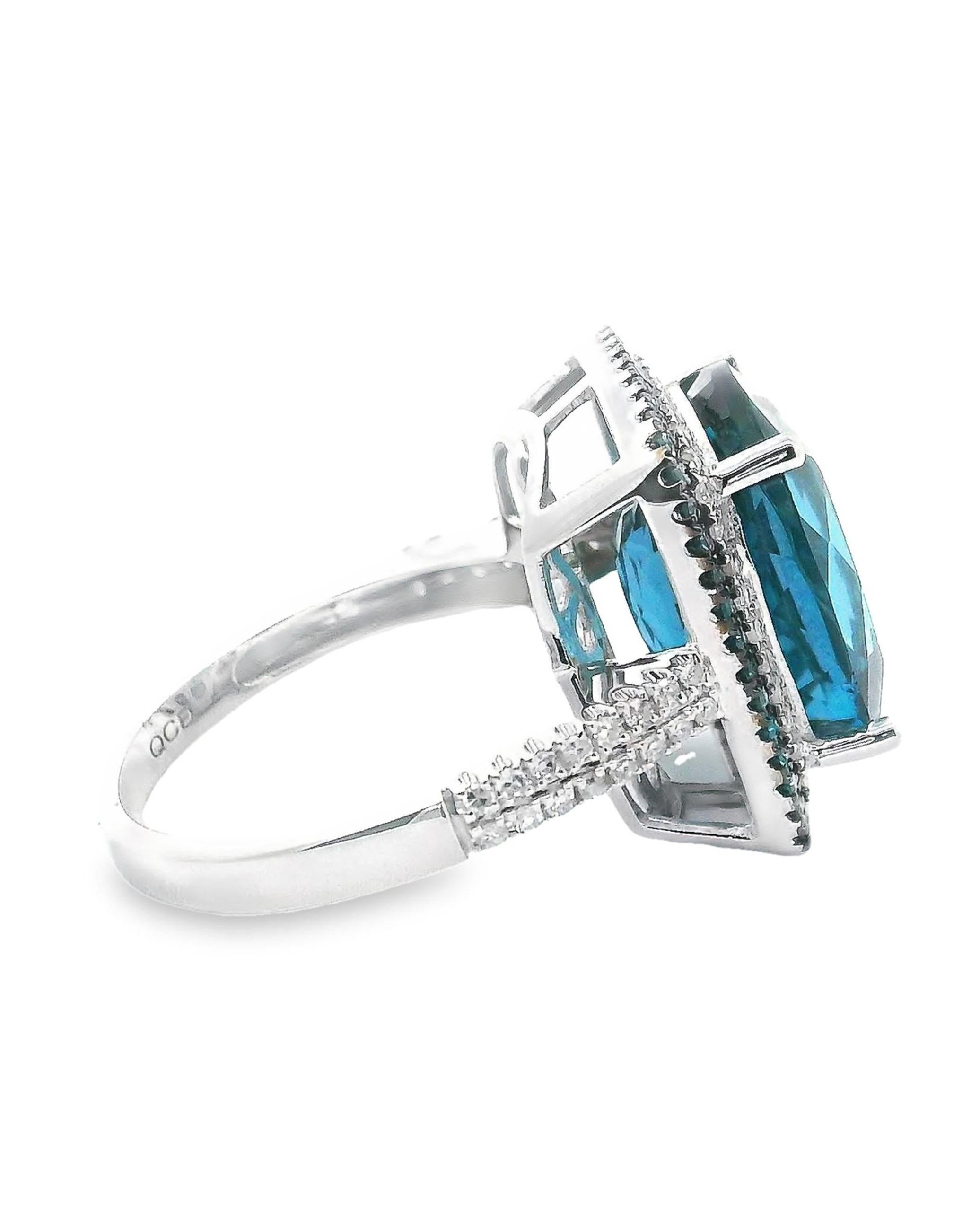 14K white gold halo fashion ring. The halo and shank are furnished with round faceted blue treated diamonds and white faceted diamonds weighing 0.54 carats total. In the center, one faceted cushion shape London blue topaz weighing 10.97 carats. 

-
