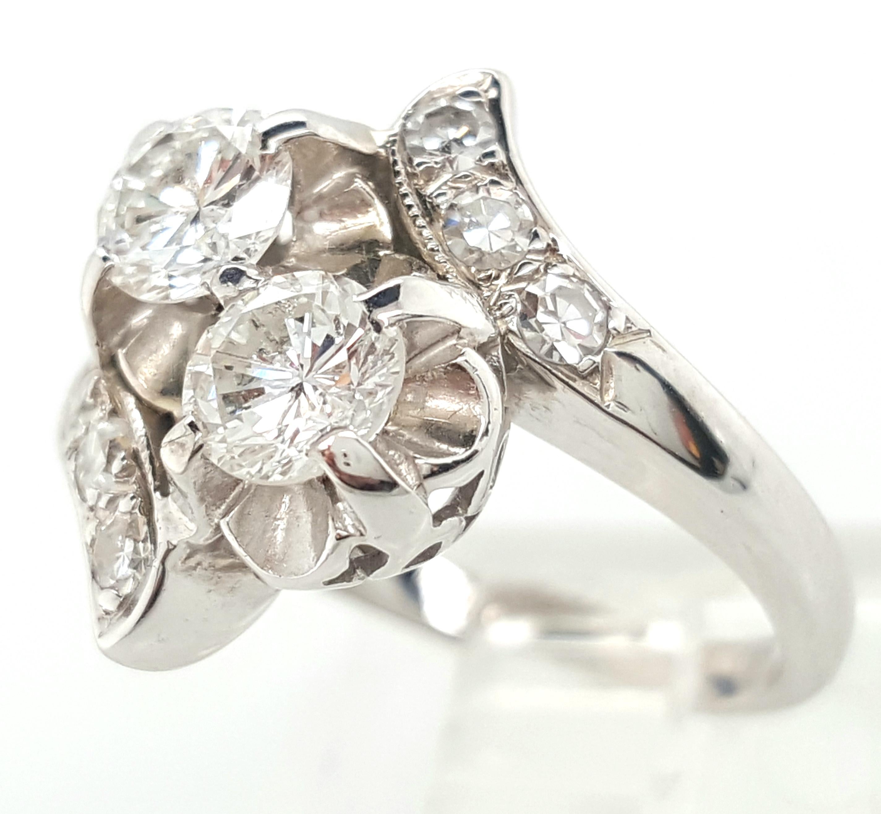 This lovely 14 karat white gold vintage bypass ring features two round brilliant cut diamonds diagonally set in a shared prong tulip setting accented by a gallery of open work in the shape of teardrops.   The diamonds weigh approximately 0.80 carats