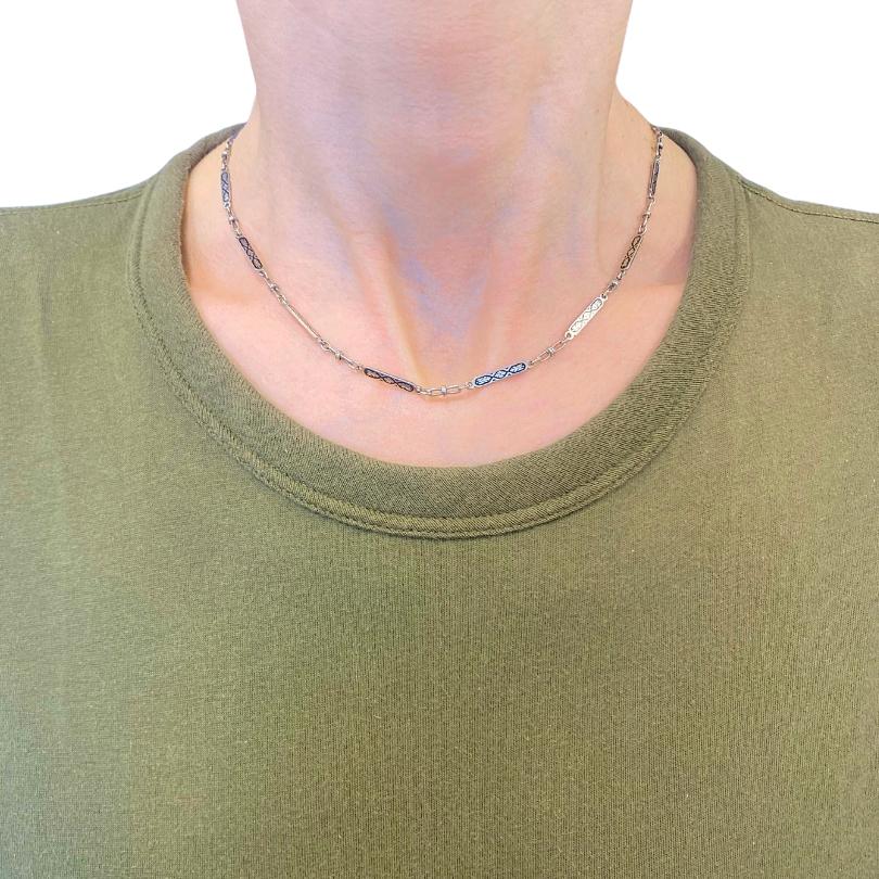 Este collar vintage de cadena de oro blanco de 14 quilates presenta una delicada serie de eslabones rectangulares alargados decorados con esmalte negro en un patrón geométrico repetitivo. Cada sección esmaltada está enmarcada por bordes de oro
