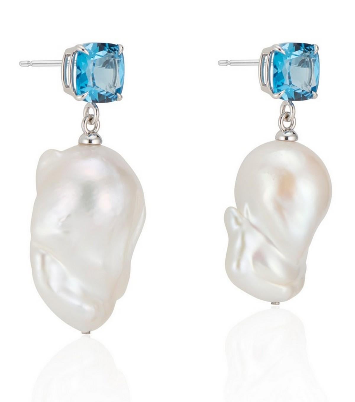 Une étonnante topaze bleue de Londres taillée en coussin est associée à une perle baroque blanche naturelle et lumineuse pour créer une boucle d'oreille romantique.

Les bijoux sont sertis dans un panier en or blanc 14k très poli, avec des griffes
